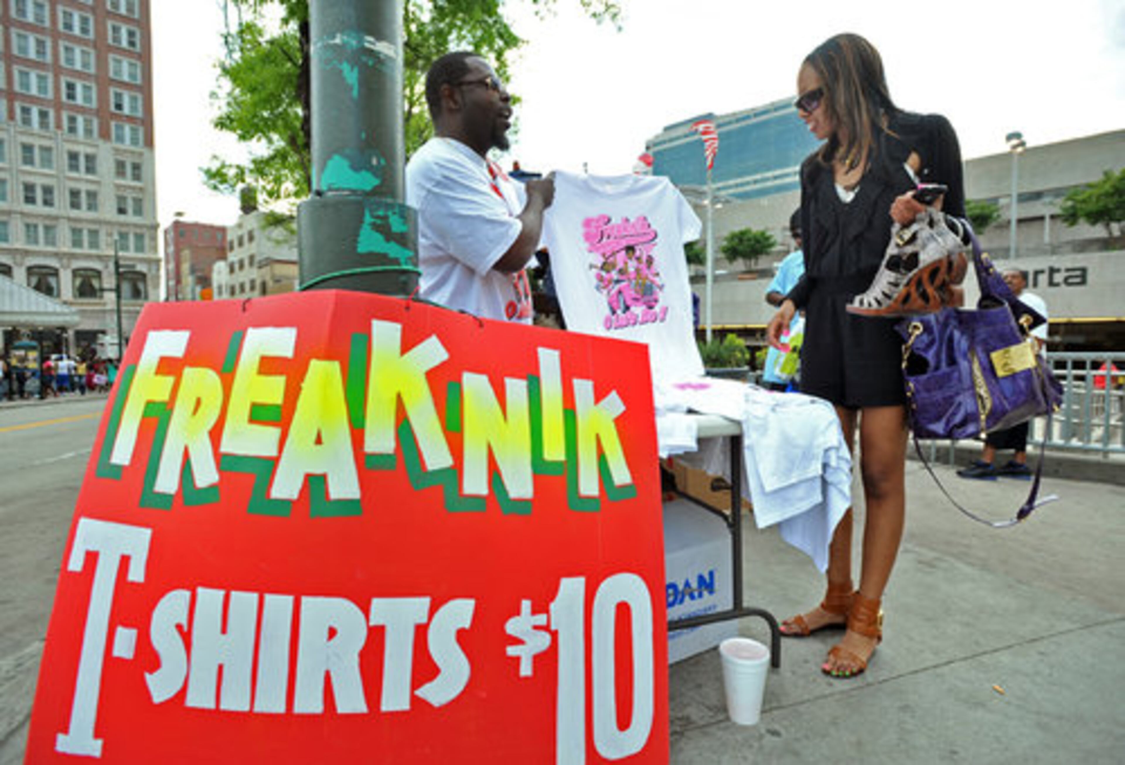 Eric Jones (left) tempts Shanell Hudson, 20, into buying a Freaknik T-shirt outside the Five Points Marta station.