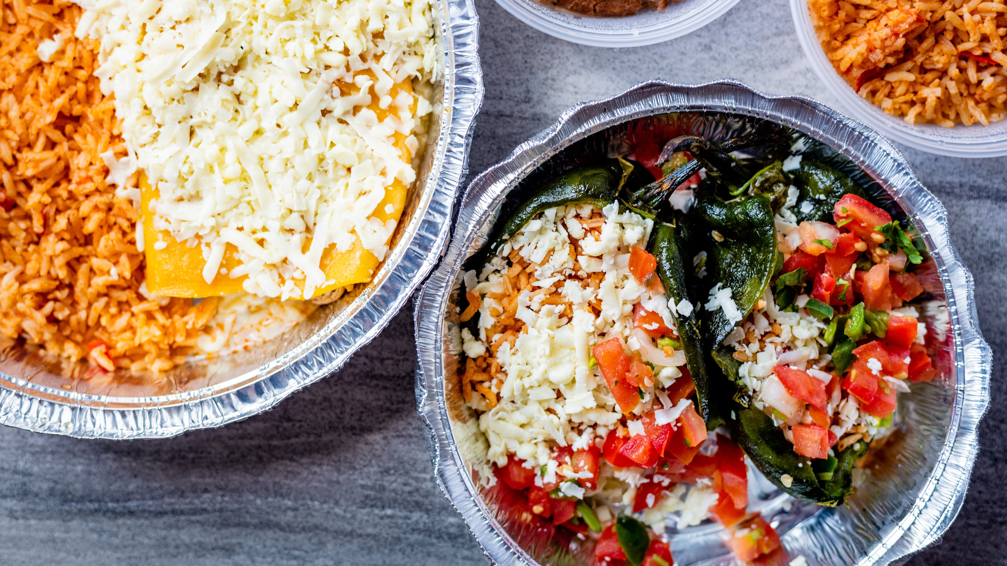 Entrees from El Ponce are prepped and ready for the oven at home, including chicken enchiladas (left) and chiles rellenos (bottom right).