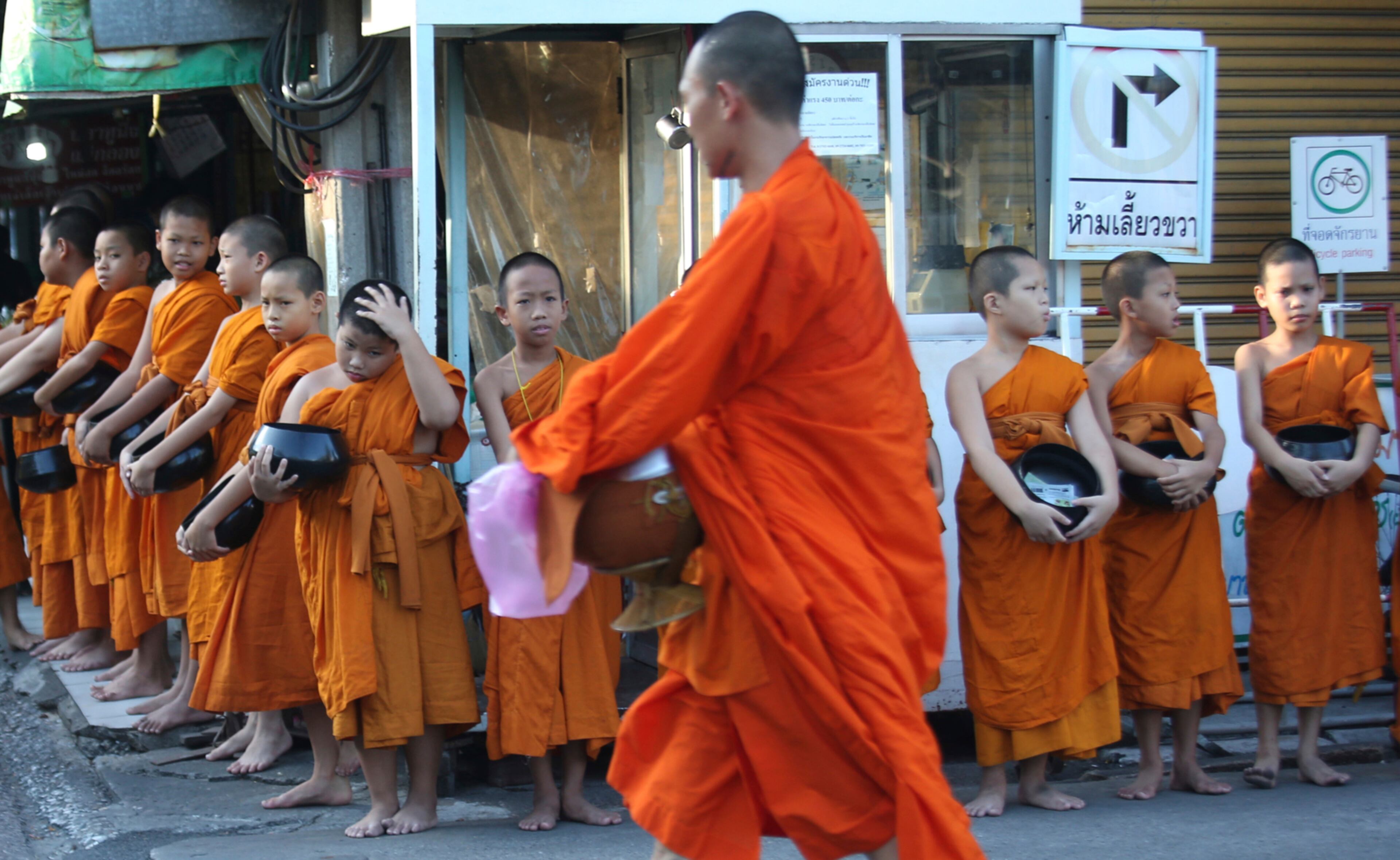 A Thai Buddhist monk walks past novice Buddhist monks during a merit in Bangkok, Thailand, Wednesday, April 19, 2017. Thai men are expected to enter the monkhood at least once during their life. (AP Photo/Sakchai Lalit)