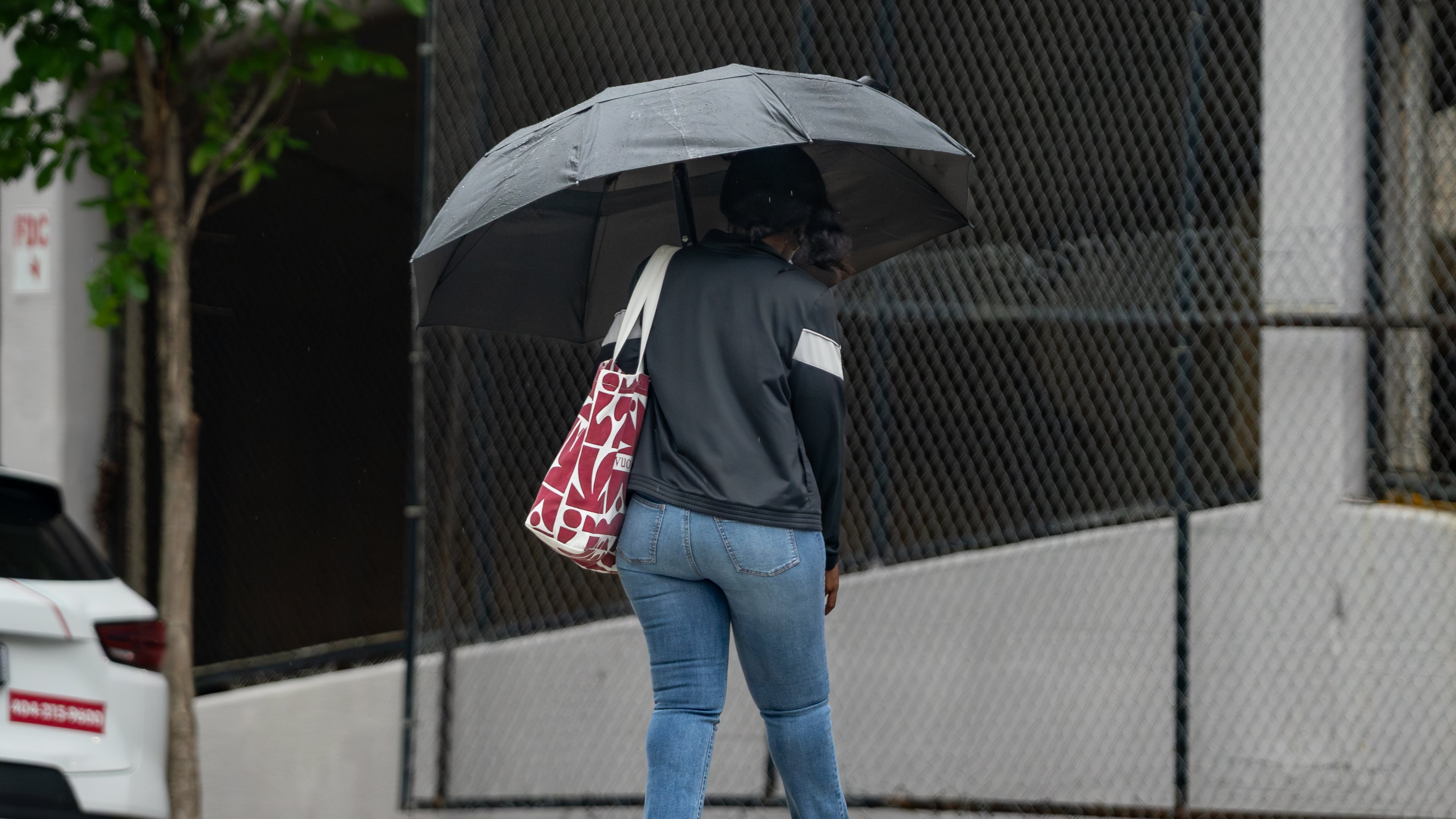 A woman with an umbrella crosses Cone Street in Atlanta during light rain on Friday, May 29, 2026. (Ben Hendren for the AJC)