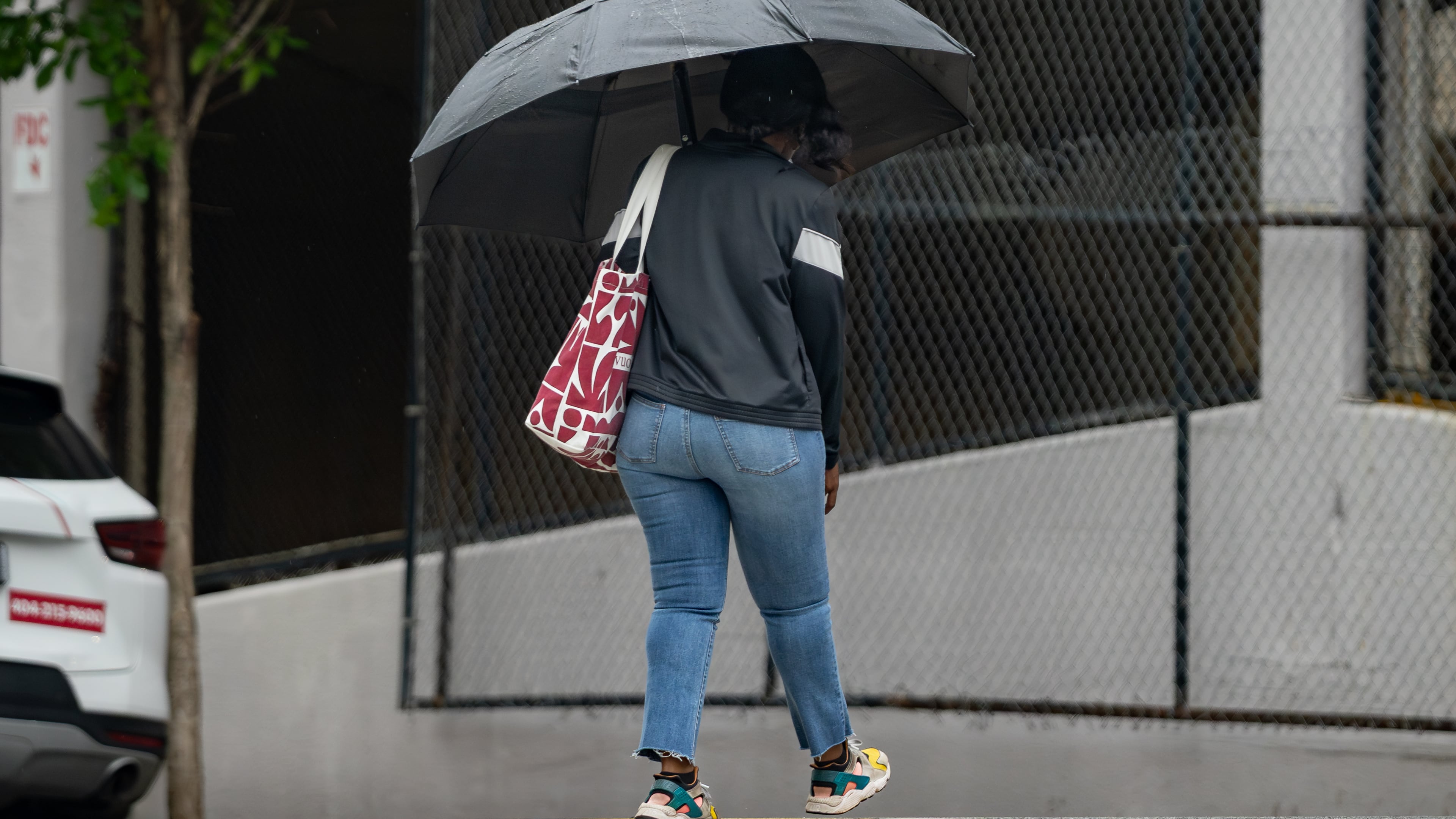 A woman with an umbrella crosses Cone Street in Atlanta during light rain on Friday, May 29, 2026. (Ben Hendren for the AJC)