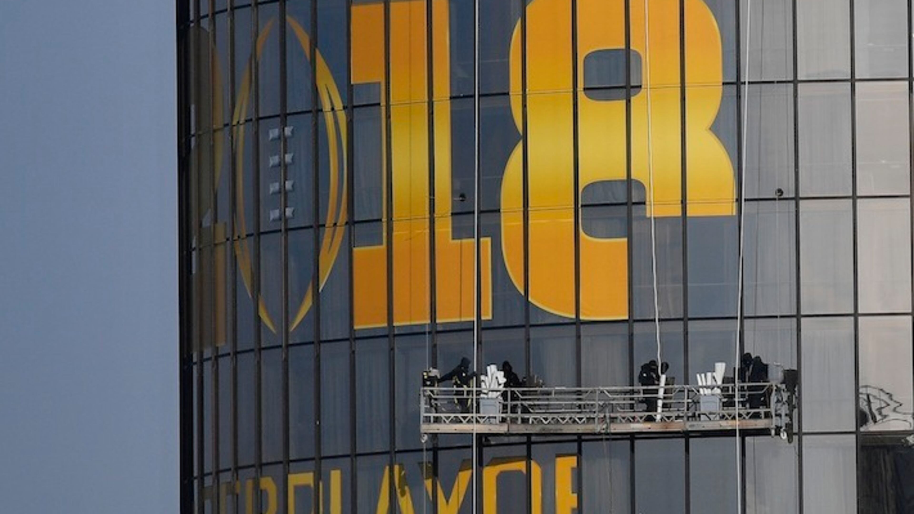 Workers place signage on a hotel announcing the NCAA national championship football game, Wednesday, Jan. 3, 2018, in Atlanta. Alabama and Georgia won their College Football Playoff semifinals on Monday and will meet in the national championship next week in Atlanta. (AP Photo/Mike Stewart)
