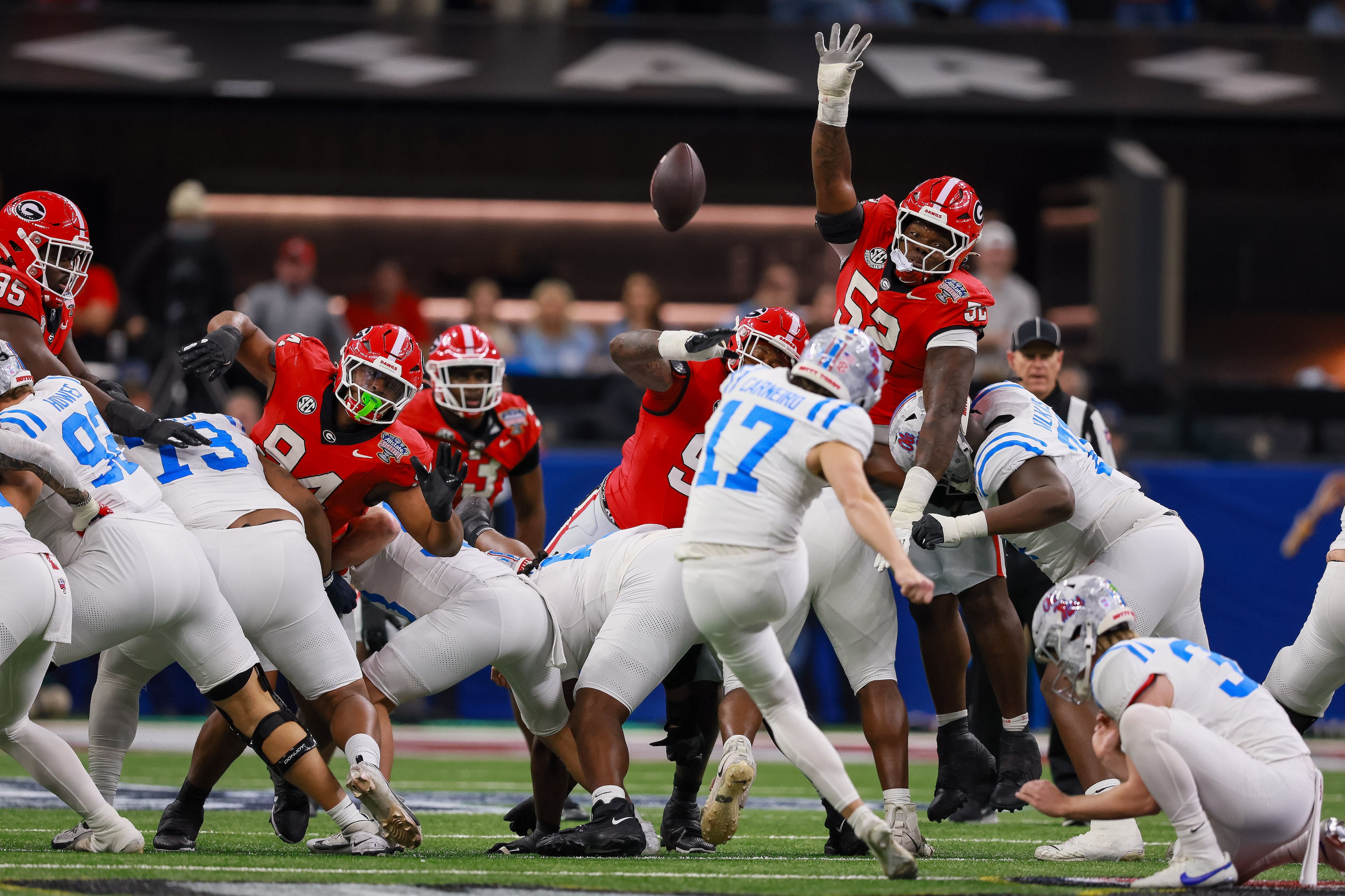 Ole Miss Rebels wide receiver Winston Watkins (17) kicks a field goal past diving Georgia Bulldogs defensive lineman Christen Miller (52) during the first quarter of the Georgia vs. Ole Miss NCAA College Football Playoff quarterfinal game at the Sugar Bowl in the Caesars Superdome, Thursday, Jan. 1, 2026, in New Orleans. (Jason Getz/AJC)