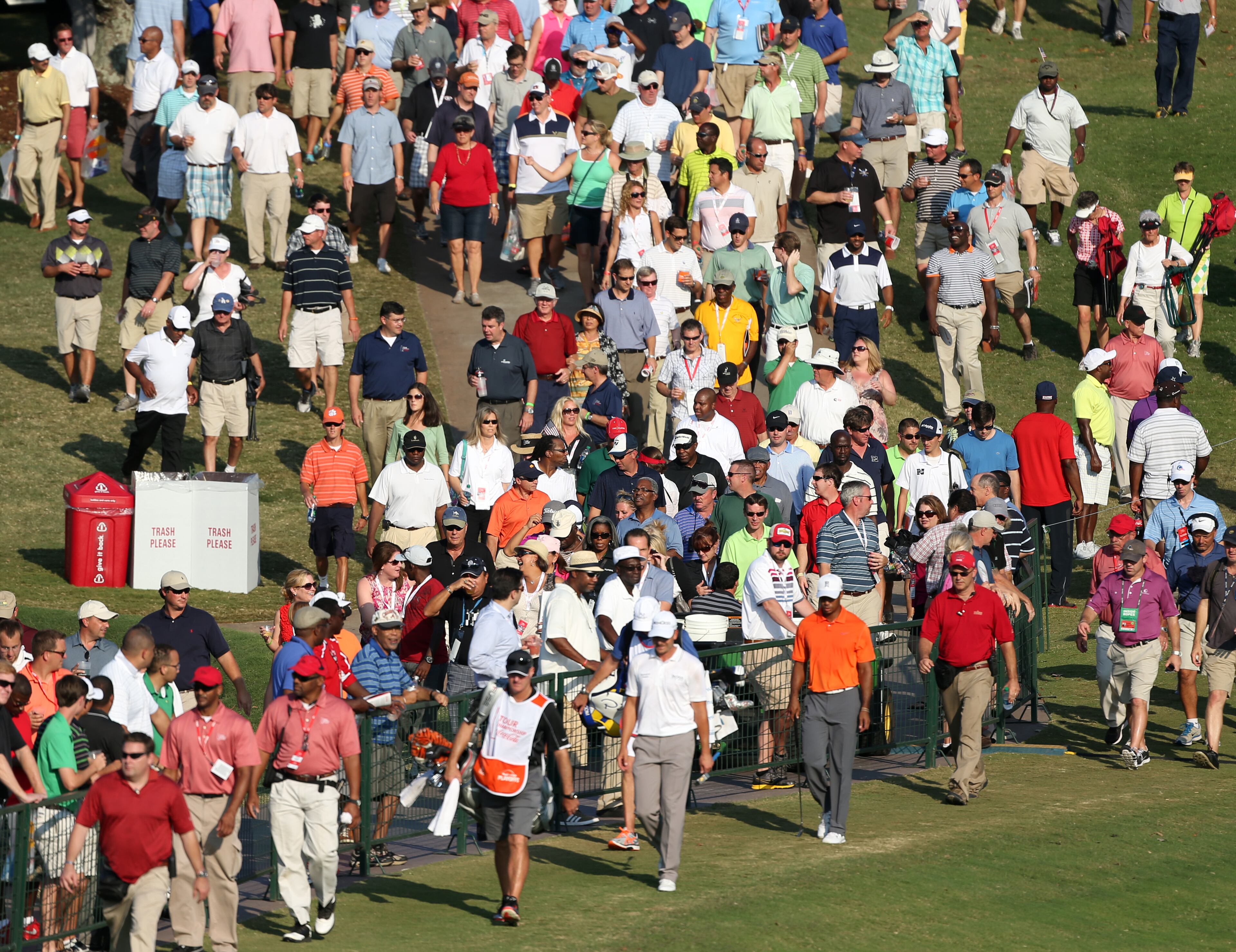 Spectators crowd the fence as Tiger Woods (in orange) walks down the No. 18 fairway during round one of the 2013 Tour Championship at East Lake Golf Club Thursday morning in Atlanta, Ga., September 19, 2013. Woods finished in 29th place with a round of 3 over par.