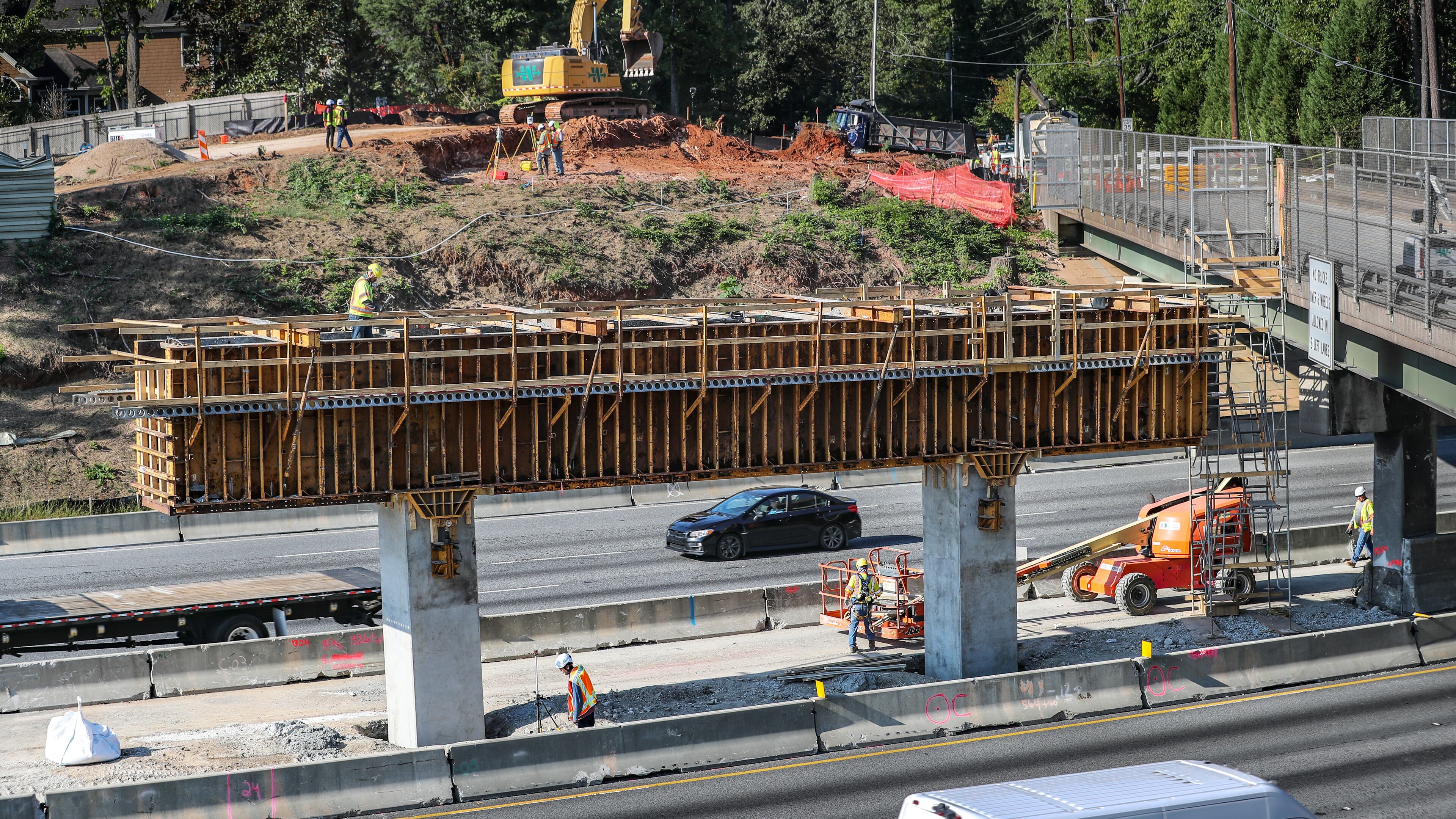 September 29, 2023 Atlanta: Construction work continued Friday, Sept. 29, 2023 on the new bridge construction as the existing Mount Vernon Highway bridge over I-285 in Sandy Springs will remain closed into next year after a tractor-trailer carrying an excavator crashed into it Wednesday, significantly damaging the bridge beams. Structural evaluations of the bridge were concluded Thursday evening, and it was determined that five of six beams were impacted and require replacement, according to Georgia Department of Transportation spokesperson Natalie Dale. Mount Vernon Highway will not reopen to vehicle or pedestrian traffic until summer 2024. “Safety of the traveling public is paramount in all Georgia DOT decisions,” Dale said. “GDOT is working with the contractor and evaluating all viable options to advance the current project timeline.” Authorities closed the bridge and the westbound I-285 lanes below after the truck clipped the overpass around noon Wednesday, snarling traffic during the evening commute and beyond. The damaged portion was secured overnight to prevent debris from falling onto the interstate, and all lanes of I-285 West reopened around 4 a.m. Thursday. The quickest way to get around the Mount Vernon Highway closure is to use Riverside Drive. Long Island Drive and Roswell Road are also good alternates, the WSB 24-hour Traffic Center reported. According to GDOT, the truck and equipment involved in the wreck were not related to the construction crews already in the area for the reconstruction of the bridge, built in 1962. Since Sept. 5, the inside lanes on both the inner and outer loop of I-285 have been closed due to work associated with the lane extension project. The project aims to add an auxiliary lane along I-285 between Roswell Road and Riverside Drive, and replace the Mount Vernon Highway bridge. The work was expected to continue until Nov. 4, but due to needed repairs and material availability, Dale said completion of the project and reopening of the overpass is now estimated to conclude next summer. (John Spink / John.Spink@ajc.com)