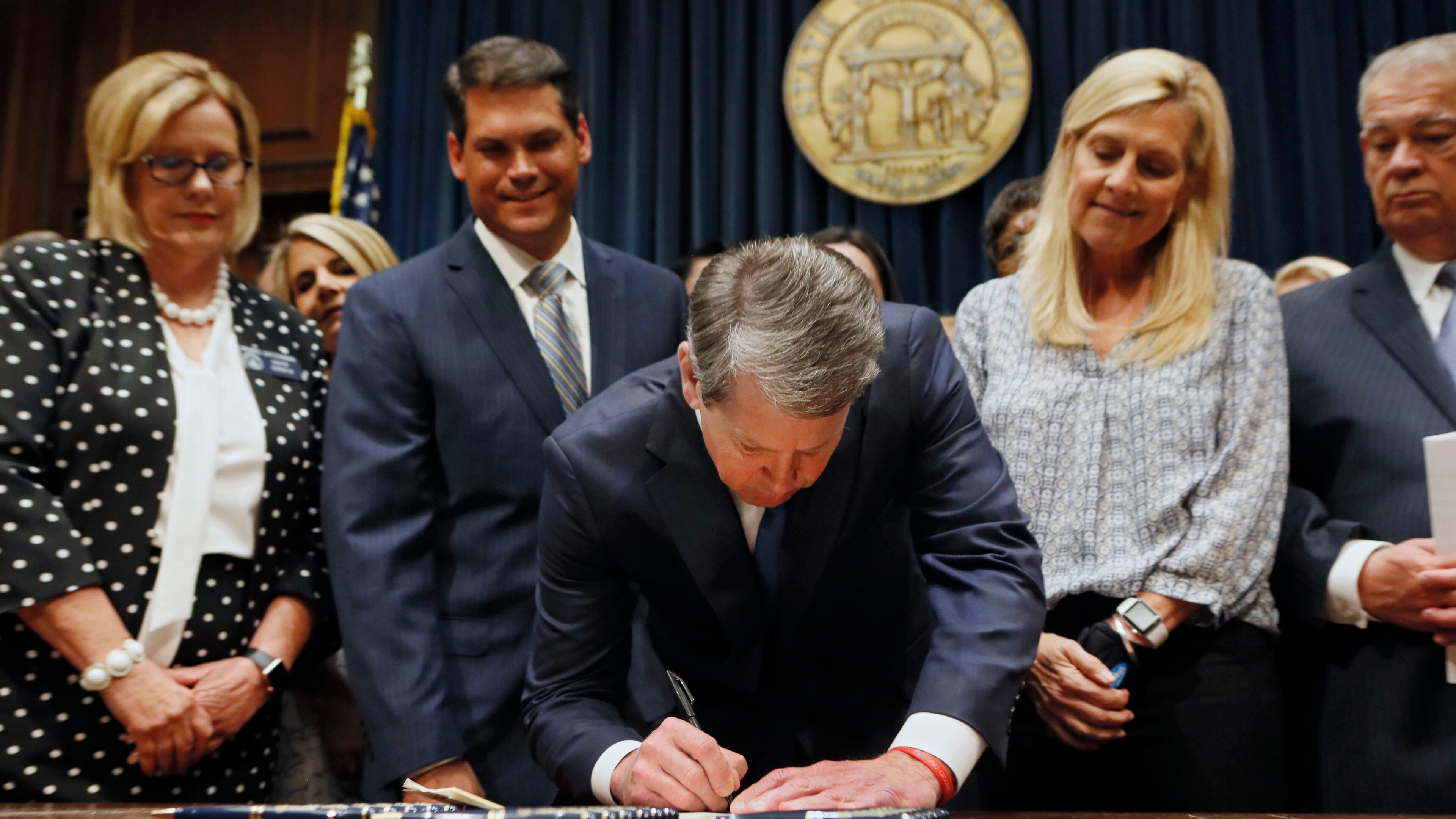 Surrounded by supporters of the bill, including state Sen. Renee Unterman (from left), R - Buford, Lt. Gov. Geoff Duncan, first lady Marty Kemp, and House Speaker David Ralston, Gov. Brian Kemp puts his signature to HB 481, the anti-abortion "heartbeat bill" in May. Bob Andres / bandres@ajc.com
