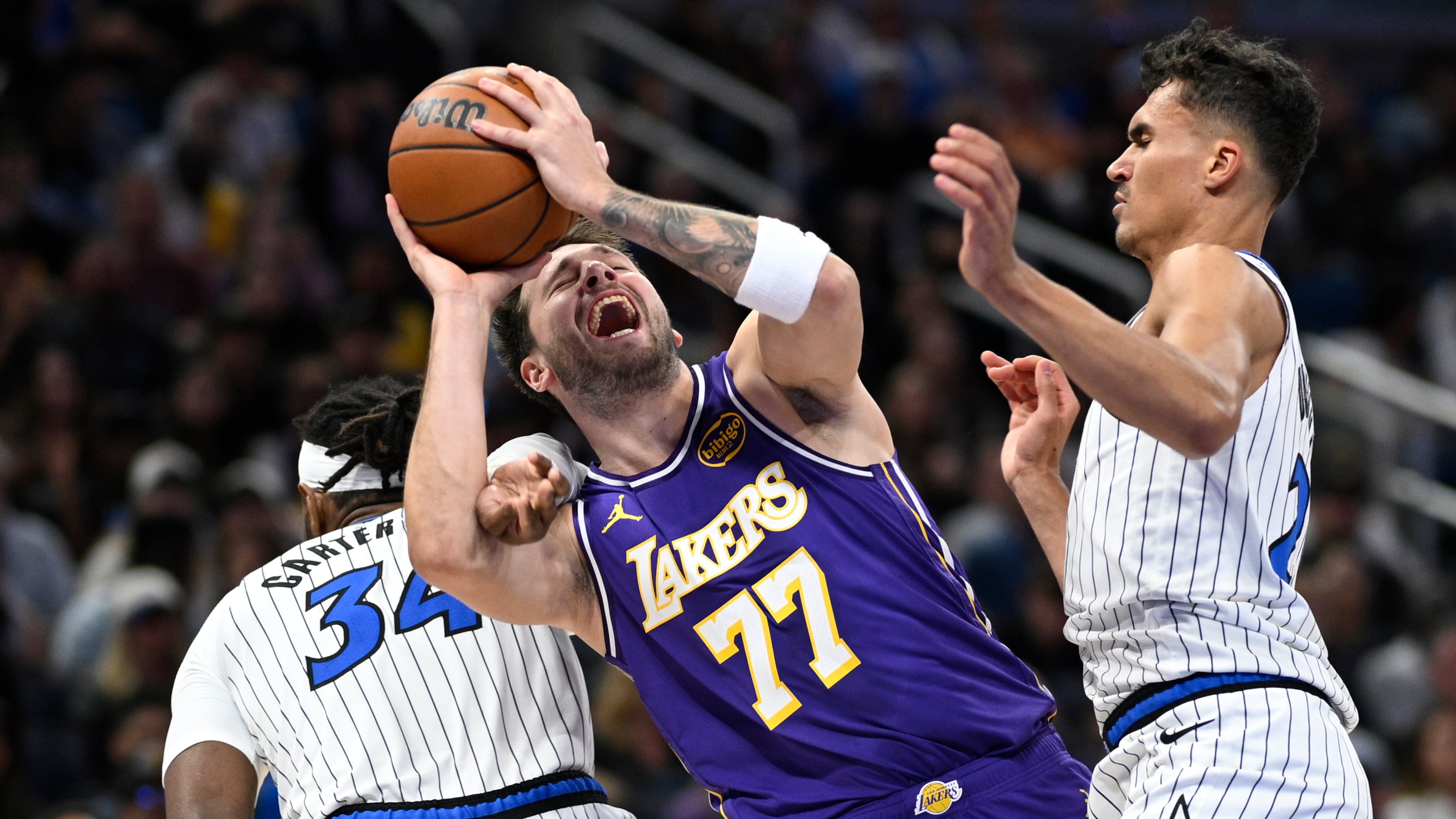 Los Angeles Lakers guard Luka Doncic (77) is fouled by Orlando Magic center Wendell Carter Jr. (34) as Magic forward Tristan da Silva, right, helps defend during the first half of an NBA basketball game, Saturday, March 21, 2026, in Orlando, Fla. (AP Photo/Phelan M. Ebenhack)