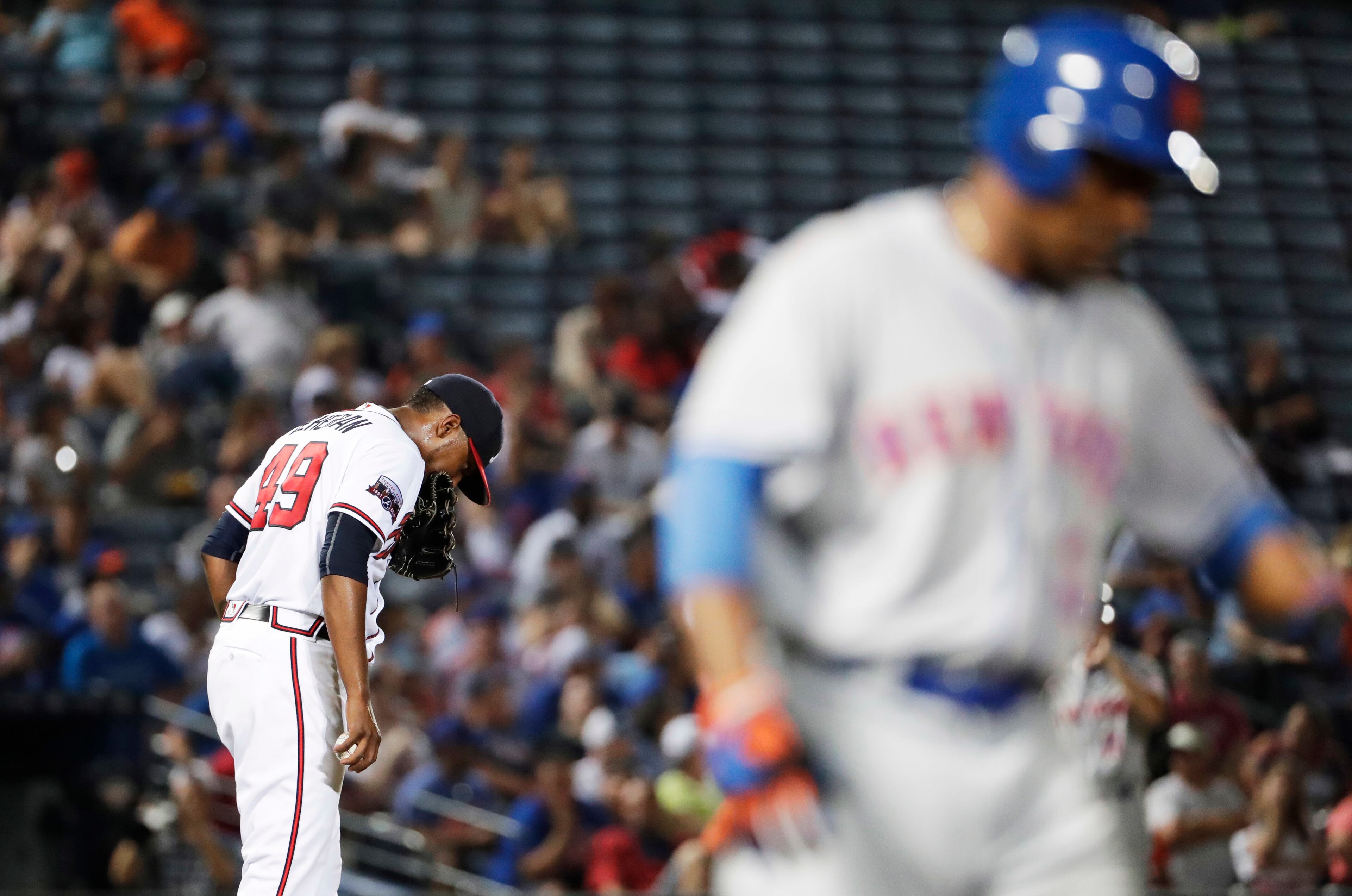 Atlanta Braves starting pitcher Julio Teheran, left, walks back to the mound after walking New York Mets' Curtis Granderson, right, during the fourth inning of a baseball game in Atlanta, Friday, Sept. 9, 2016. (AP Photo/David Goldman)