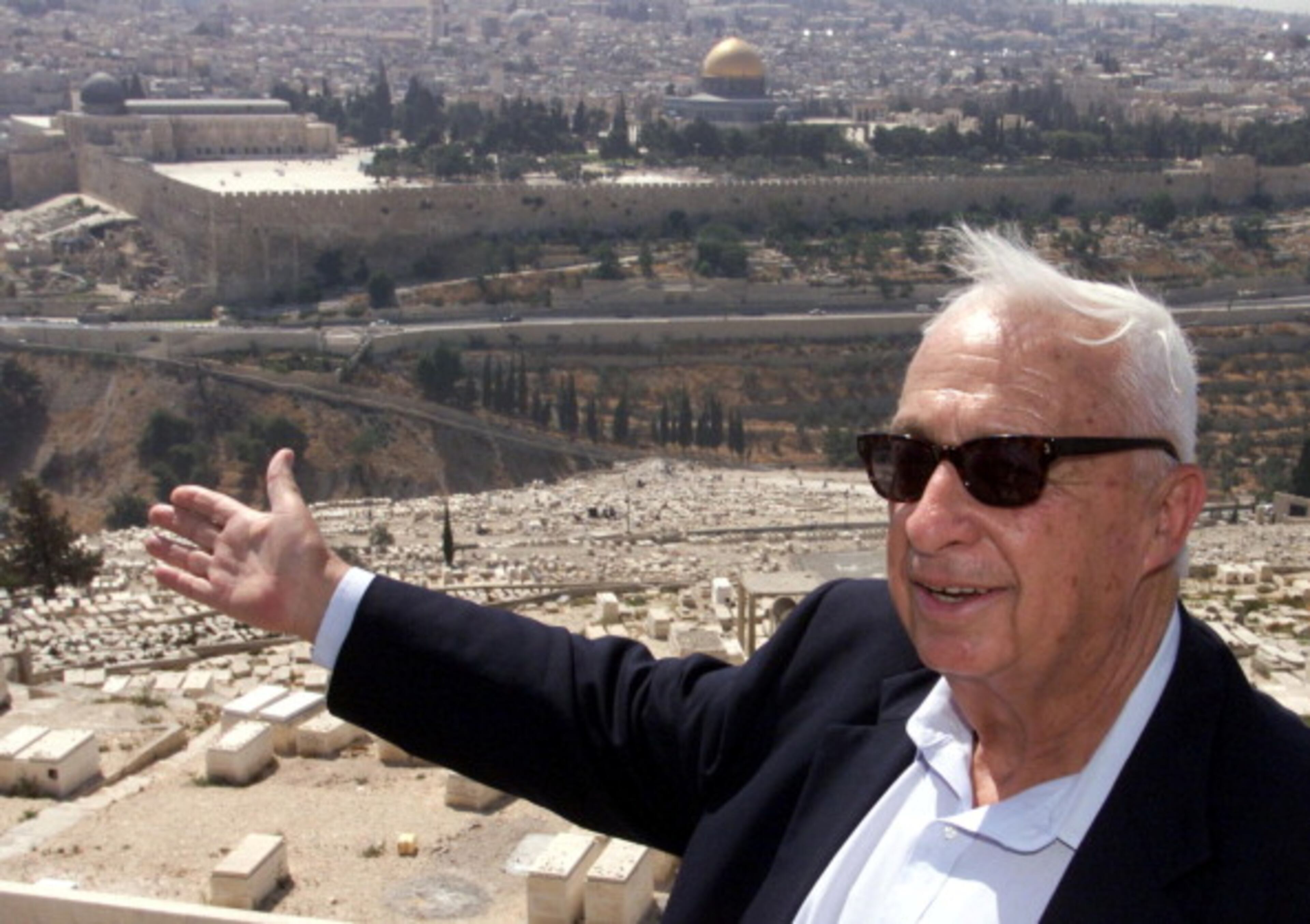 Opposition leader Ariel Sharon of the right-wing Likud gestures towards Jerusalem's Old City 24 July 2000 on the Mount of Olives during a rally to protest any land concessions in Jerusalem to the Palestinians. Israeli and Palestinian negotiators at the Camp David Middle East peace talks are reportedly mulling unofficial US suggestions that aims to bridge an ominous gap on east Jerusalem by calling for joint control over the sector. (Photo credit should read MENAHEM KAHANA/AFP/Getty Images)