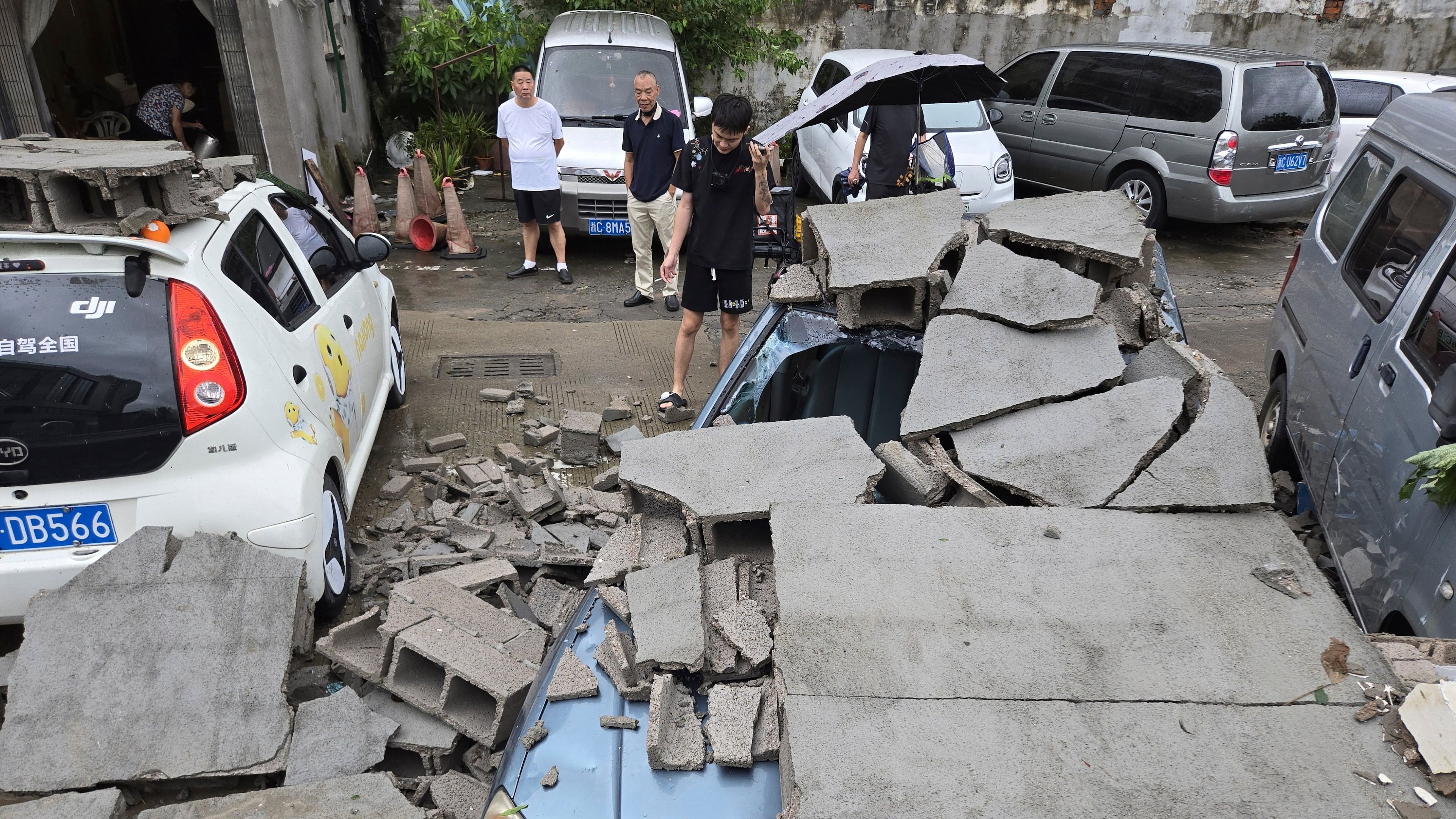 Residents view cars damaged by a fallen wall in the aftermath of Typhoon Dolphin in Wenzhou in eastern China's Zhejiang province, Monday, Aug. 10, 2026. (Chinatopix via AP)