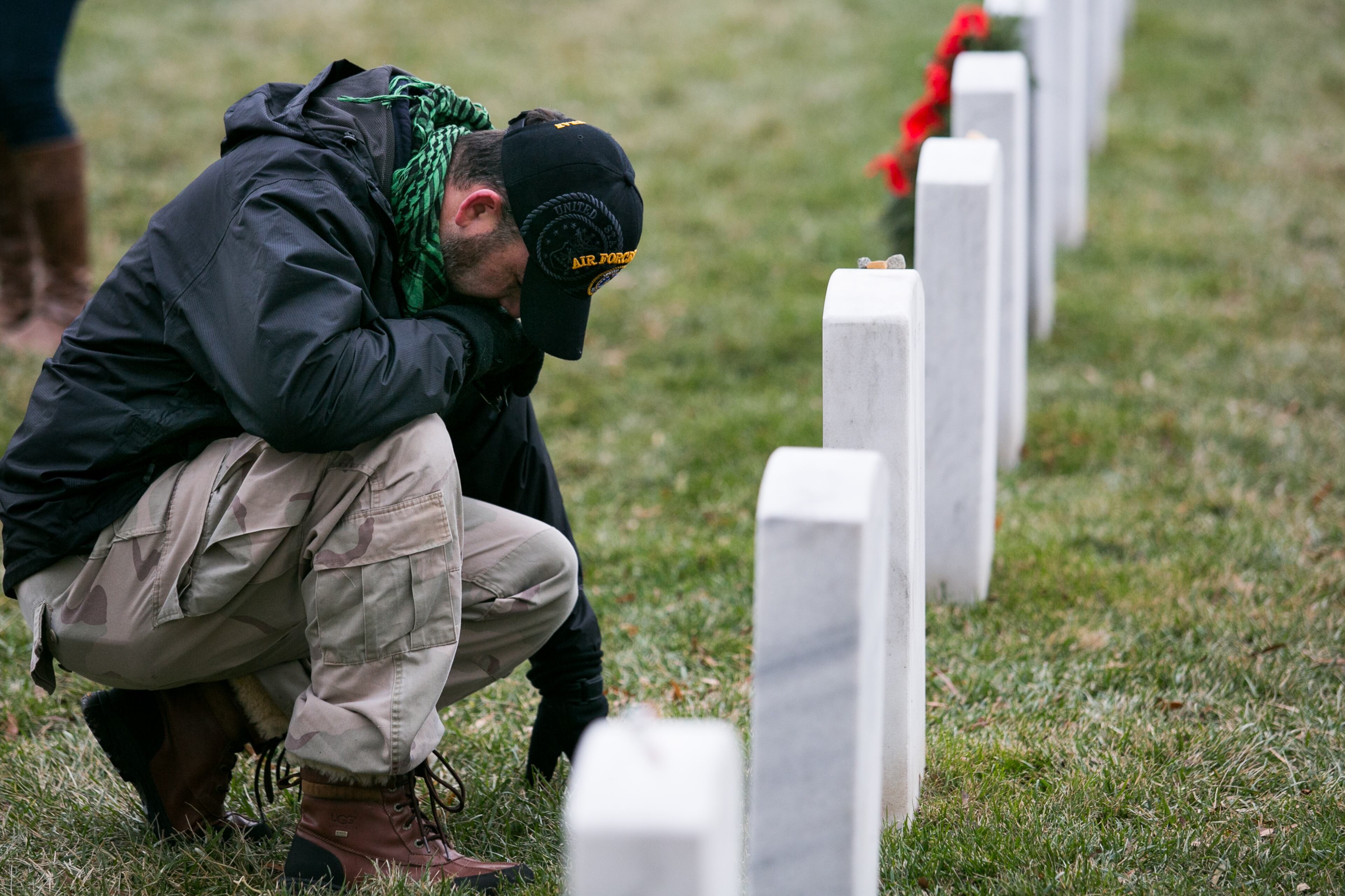 ARLINGTON, VA - DECEMBER 14: Ty Lloyd, of Potomac, Maryland, kneels at the headstone of Army Capt. Brian Matthew Bunting, in Section 60 of Arlington National Cemetery, December 14, 2013 in Arlington, Virginia. Lloyd was neighbors with Bunting's family. Bunting died February 24, 2009, in Kandahar, Afghanistan, of wounds suffered when an improvised explosive device detonated near his vehicle. Volunteers and families of the fallen placed thousands of remembrance wreaths on headstones throughout the cemetery on National Wreaths Across America Day. (Photo by Drew Angerer/Getty Images)