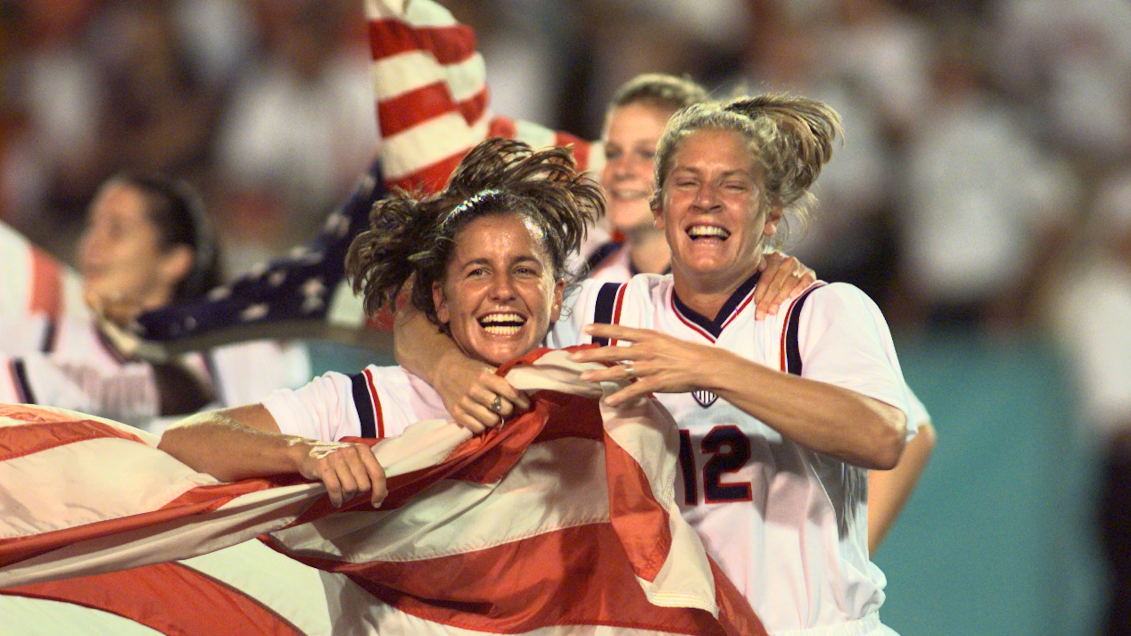 Joy Fawcett (left) and Carin Gabarra (right) run around Sanford Stadium in Athens with an American flag after their historic 2-1 gold medal win over China during the 1996 Summer Olympic Games. (David Tulis/AJC)