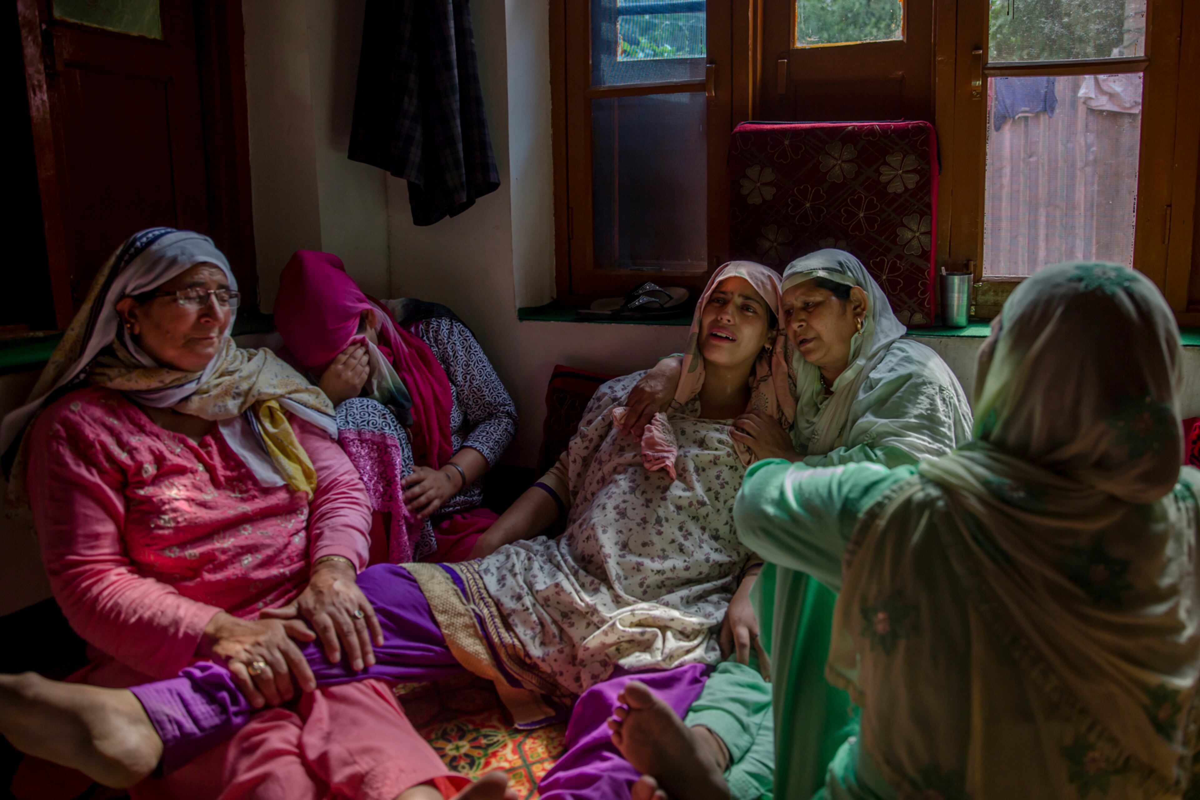 Unidentified relatives comfort wailing Rukaya Firdous, pregnant wife of a Kashmiri civilian who was killed during a protest near the site of gun battle at her residence in Begumbagh, about 32 kilometers (20miles) south of Srinagar, Indian controlled Kashmir, Tuesday, Aug. 1, 2017. Large anti-India protests and clashes spearheaded mostly by students erupted in disputed Kashmir on Tuesday after government forces killed two senior militants in a gunbattle and fatally shot a protester during an ensuing demonstration demanding an end to Indian rule. (AP Photo/Dar Yasin)