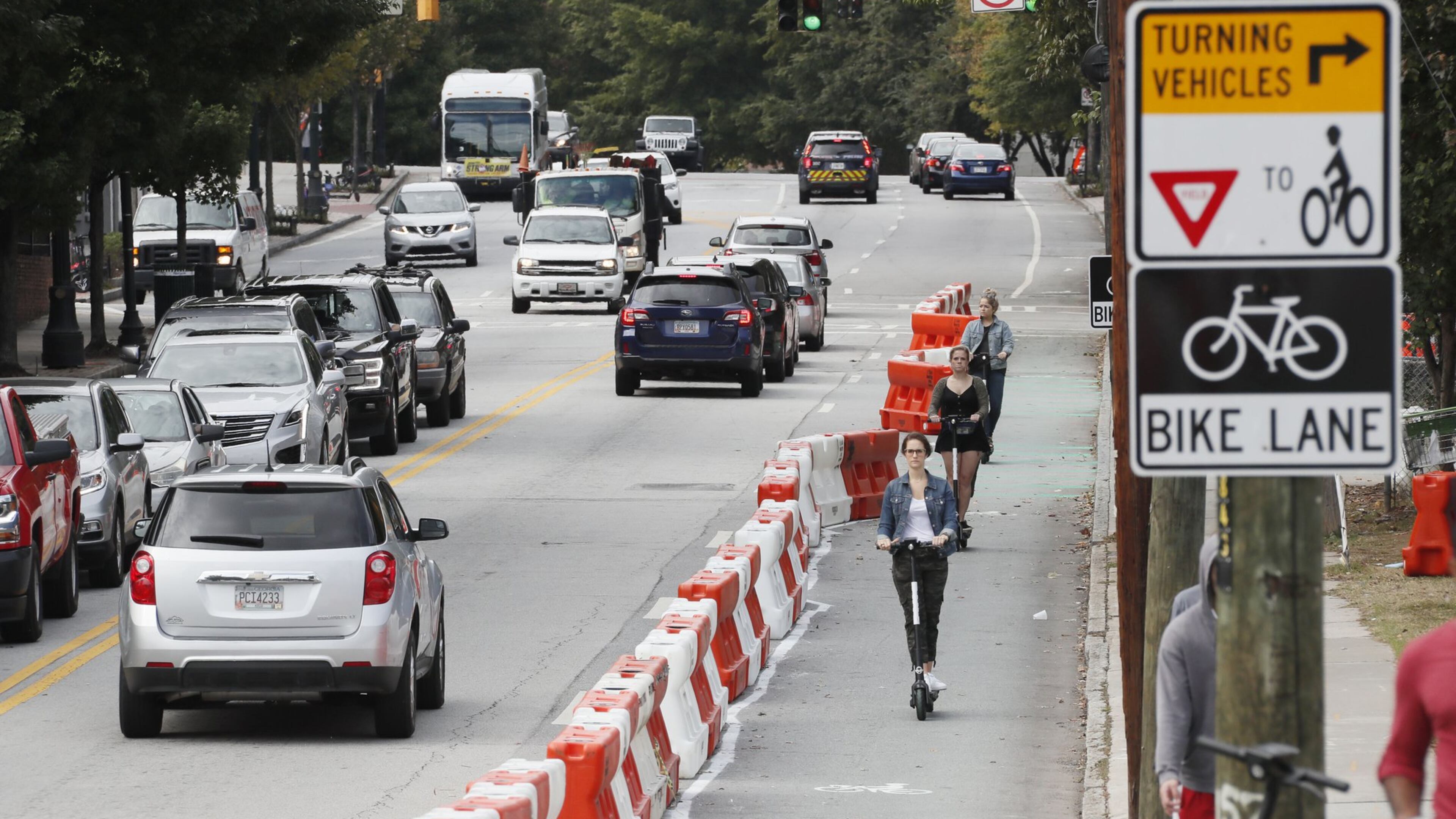 E-scooter riders make their way down 10th Street in the lane that was restricted to bikes and scooters for a week in October. The temporary bike lane was a part of the mayor’s $5 million plan to triple the city’s network of protected lanes for bicycles and scooters by the end of 2021. BOB ANDRES / ROBERT.ANDRES@AJC.COM