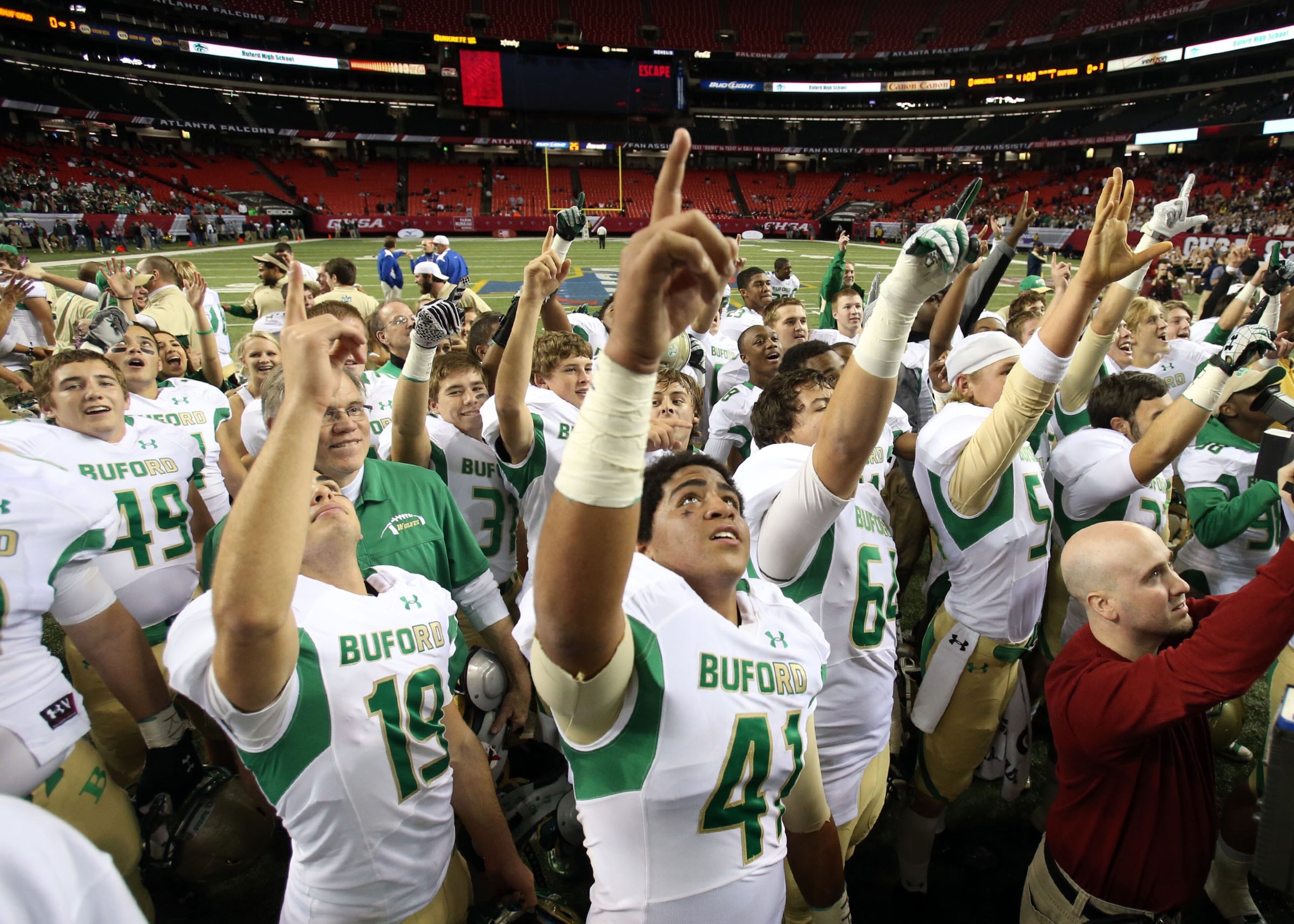 Buford players, including Colston Vukanovich (19) and Jordan Perlotte (41), point upward as they honor the memory of assistant coach Ryan Daniel, who passed earlier this year.