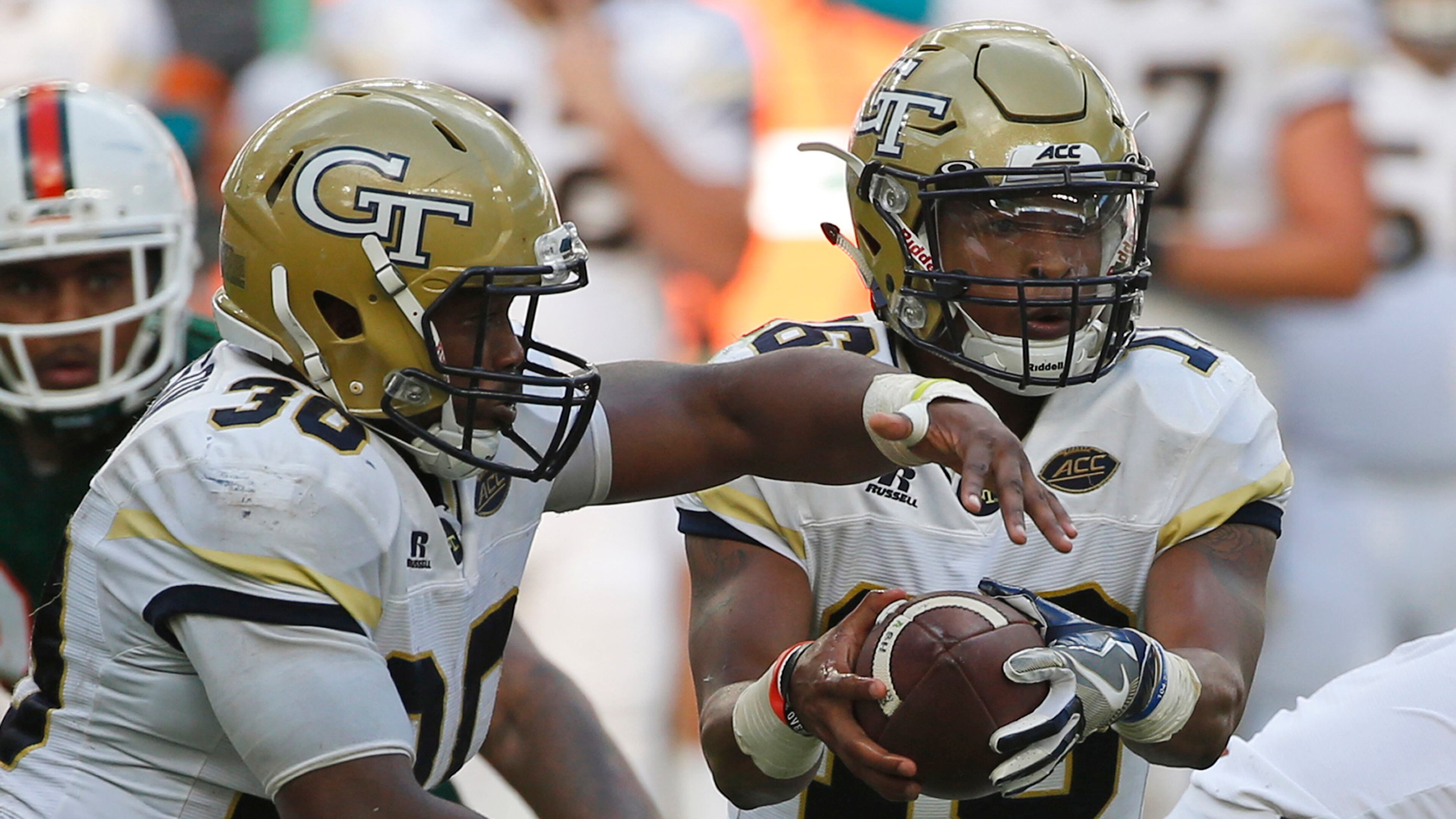 Georgia Tech quarterback TaQuon Marshall (right) fakes a handoff to running back KirVonte Benson (30) against Miami, Saturday, Oct. 14, 2017 in Miami Gardens, Fla.