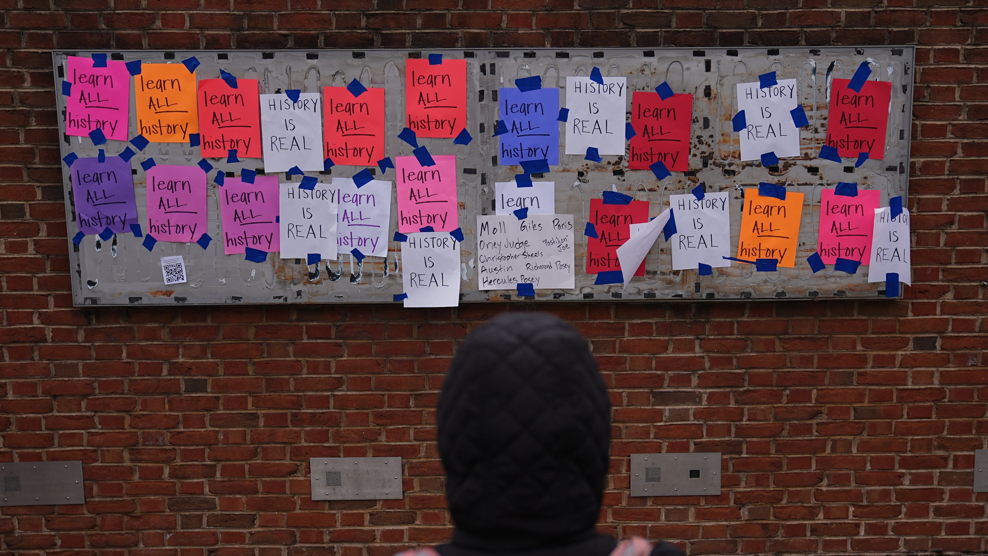 FILE - A person views posted signs on the locations of the now removed explanatory panels that were part of an exhibit on slavery at President's House Site in Philadelphia, Jan. 23, 2026. (AP Photo/Matt Rourke, File)
