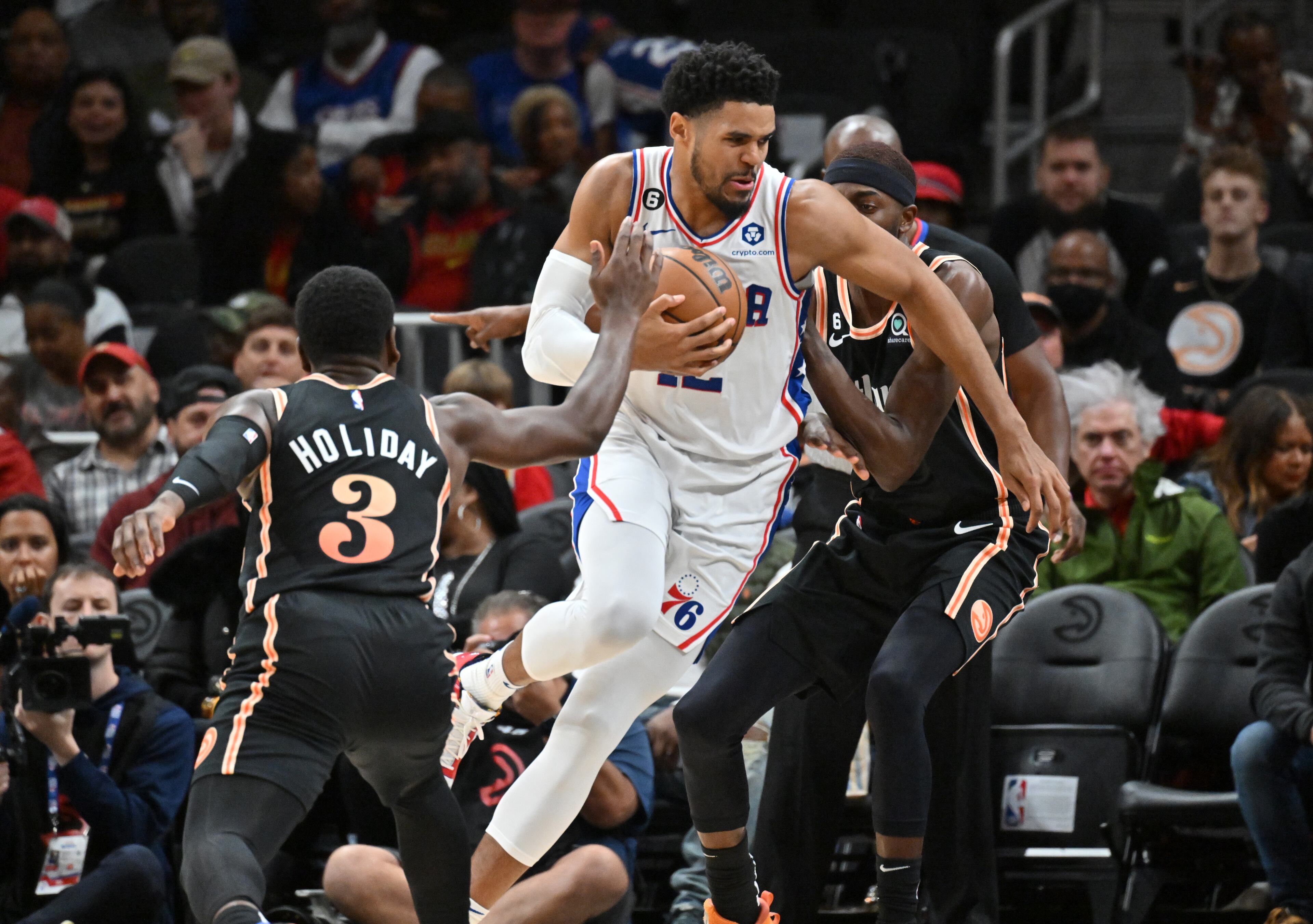 Philadelphia 76ers' forward Tobias Harris (12) dribbles against Hawks Aaron Holiday (3) and Justin Holiday (right). (Hyosub Shin / Hyosub.Shin@ajc.com)