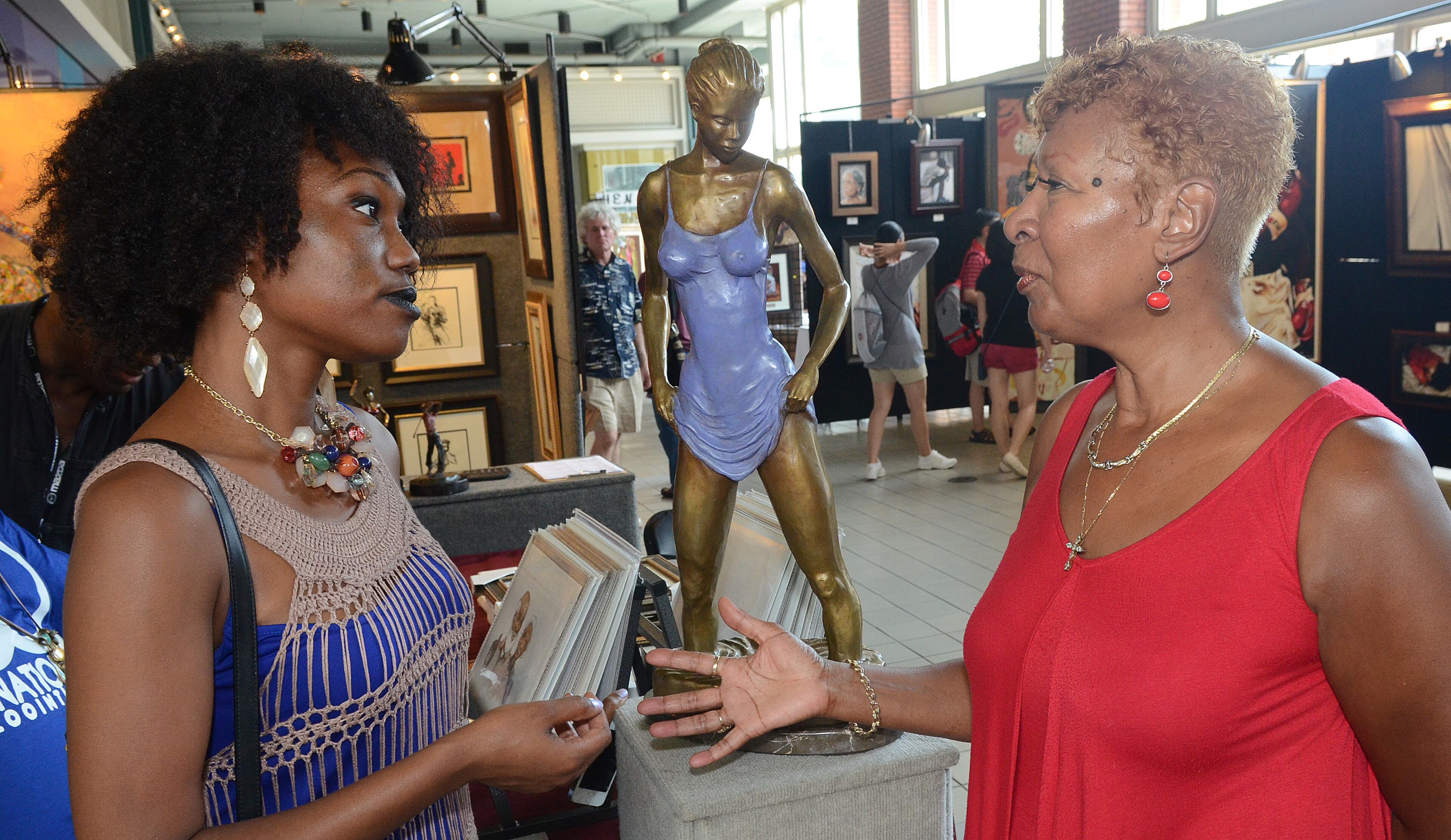 Ashley Logan (left) and Mary Rozier discuss the business of art and the challenges faced during the 19th Annual Heritage Arts and Soul Festival at Underground Atlanta. The event features the work of over 30 artist, featuring fine art and wearable art ,plus an emerging artist pavilion and fashion show. (CHRIS HUNT/SPECIAL)