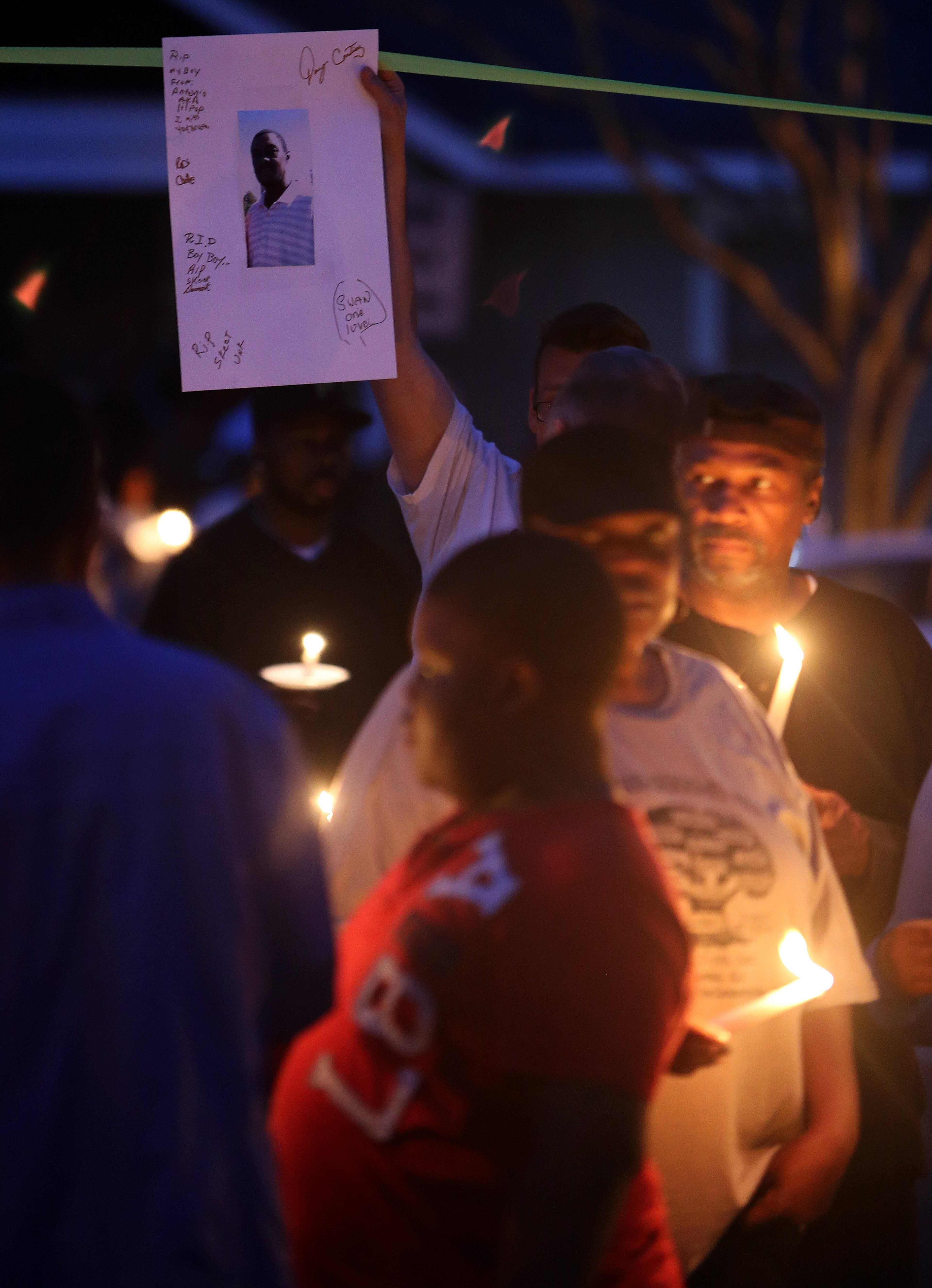 A man holds up a photo of Kelcey "Skeet" Thornton during a candle light vigil at the spot in the Peoplestown neighborhood of Atlanta where he was shot and killed Sunday evening. Family, friends and neighbors held a vigil for the man Tuesday evening March 11, 2014.