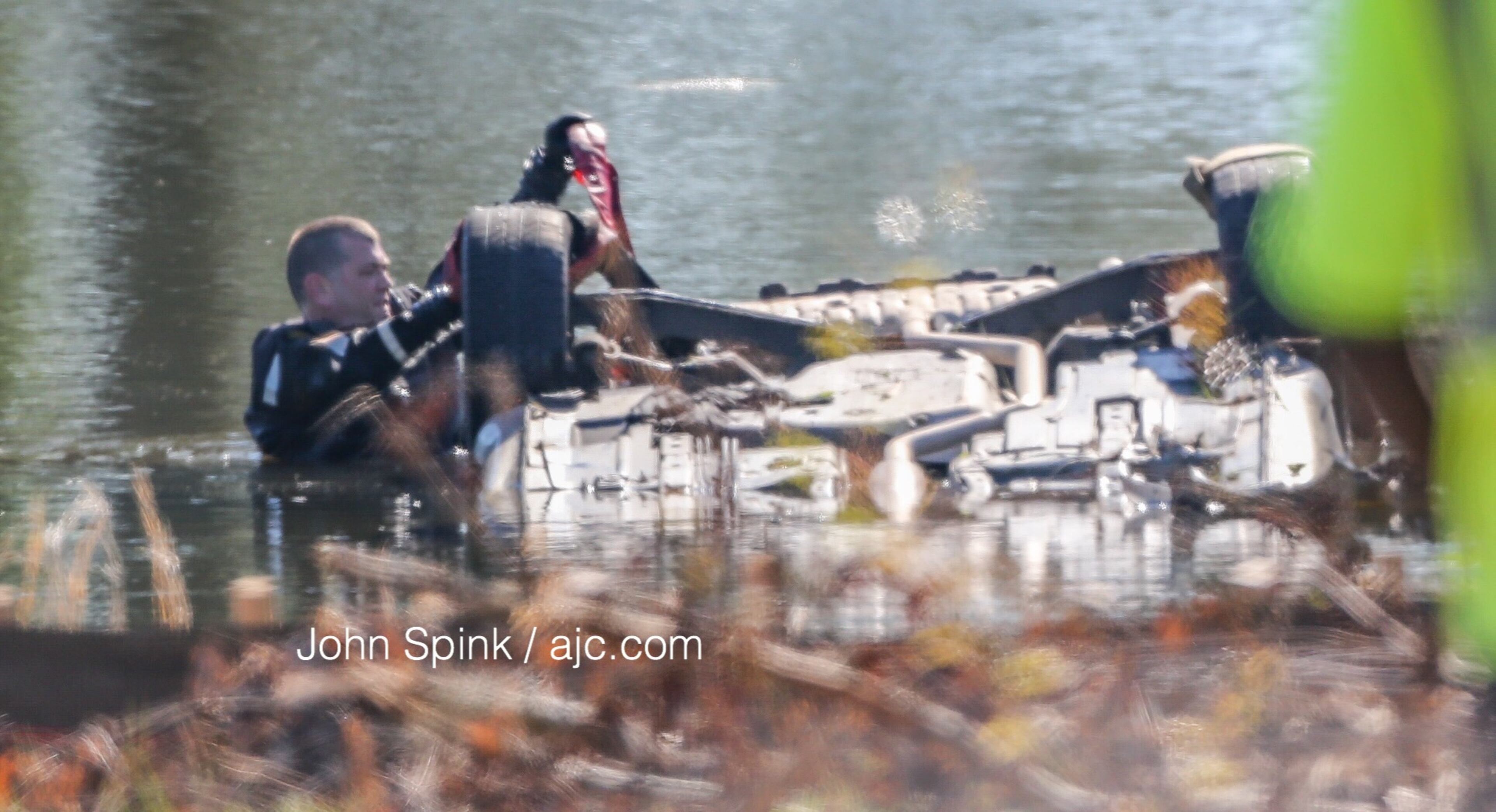 A diver checks out the wreckage Monday in a pond near the Flint River. JOHN SPINK / JSPINK@AJC.COM