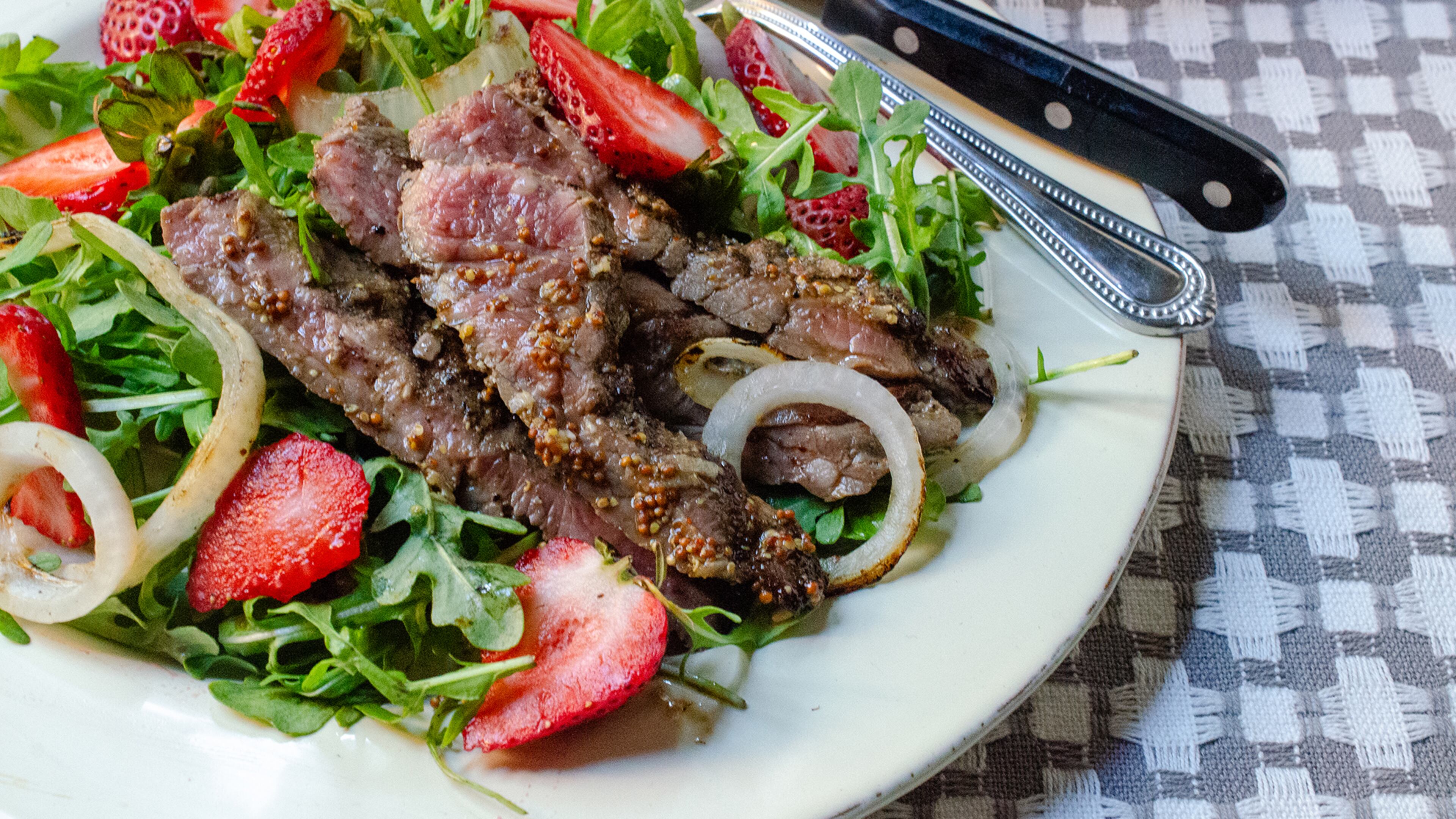 Sweet tart strawberries are paired with grilled skirt steak, Vidalia onions and balsamic vinaigrette for a hearty salad supper.
(Virginia Willis for The Atlanta Journal-Constitution)