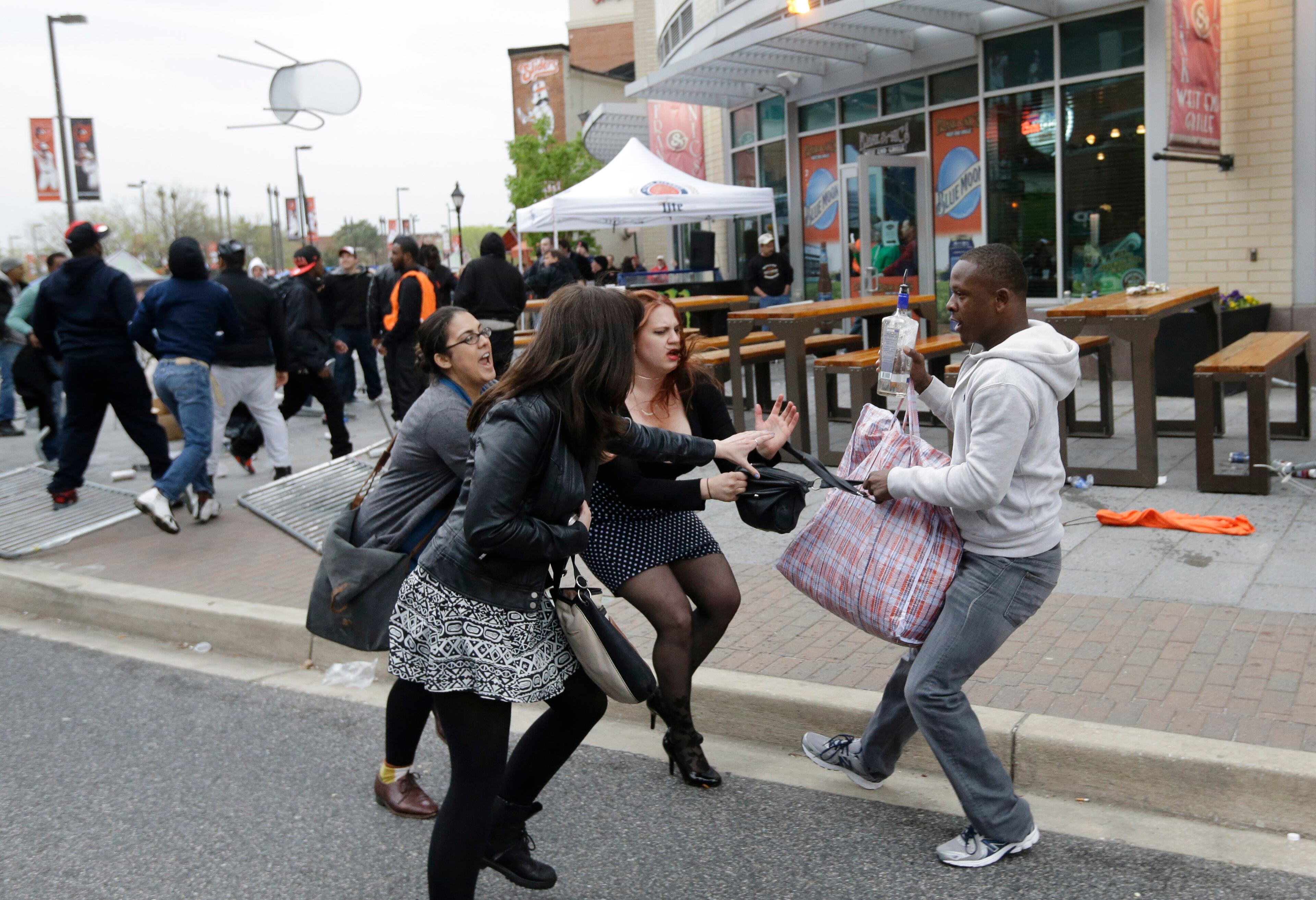 A protestor, right, pulls a bag away from a group of women after a rally for Freddie Gray, Saturday, April 25, 2015, in Baltimore. Gray died from spinal injuries about a week after he was arrested and transported in a police van. (AP Photo/Patrick Semansky)