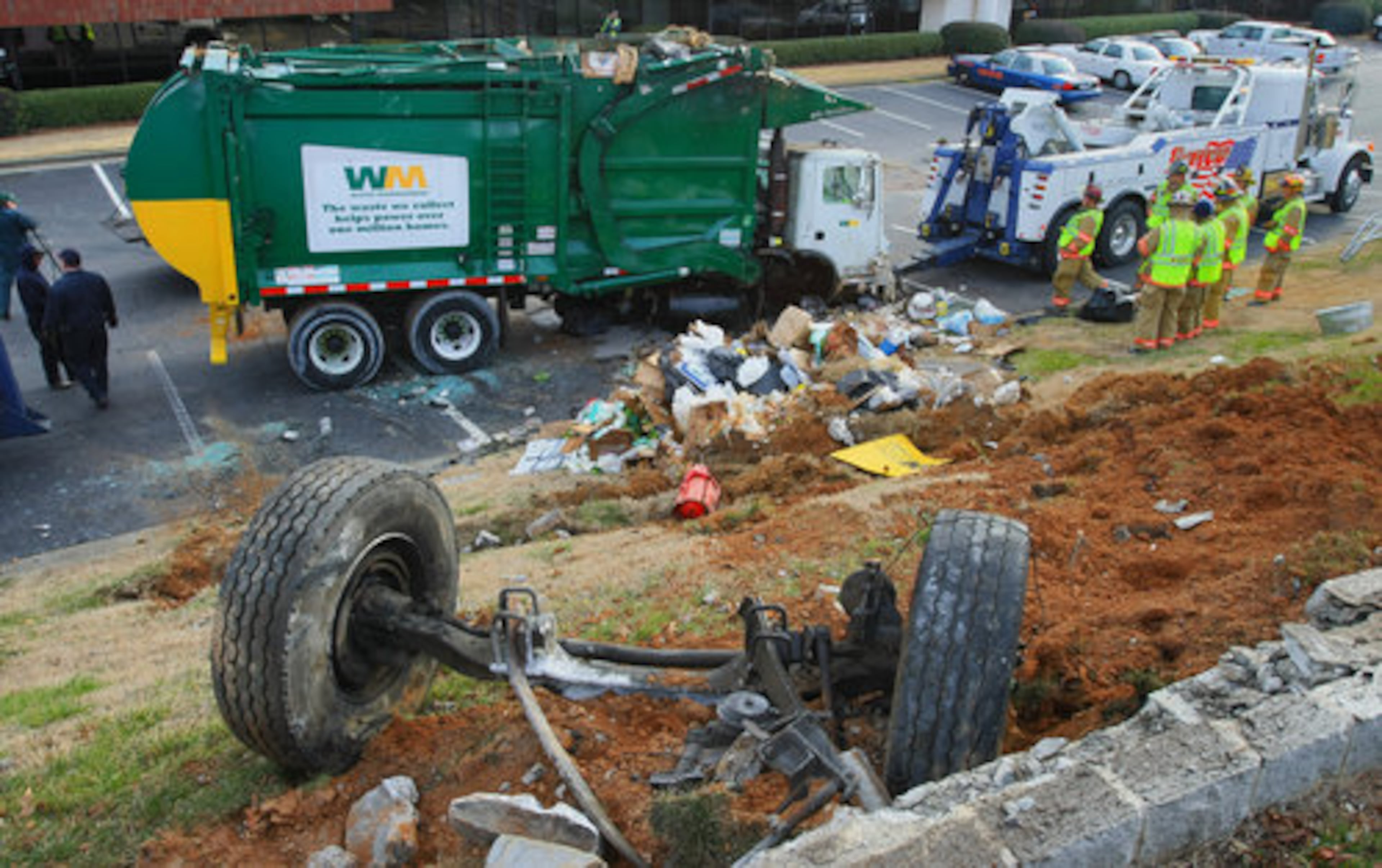 A driver of a garbage truck with Waste Management crossed the median of South Atlanta Road Monday morning and struck a utility pole and then guardrail, overturning over an embankment and onto two parked cars at the Vinings Perimeter Business Park.