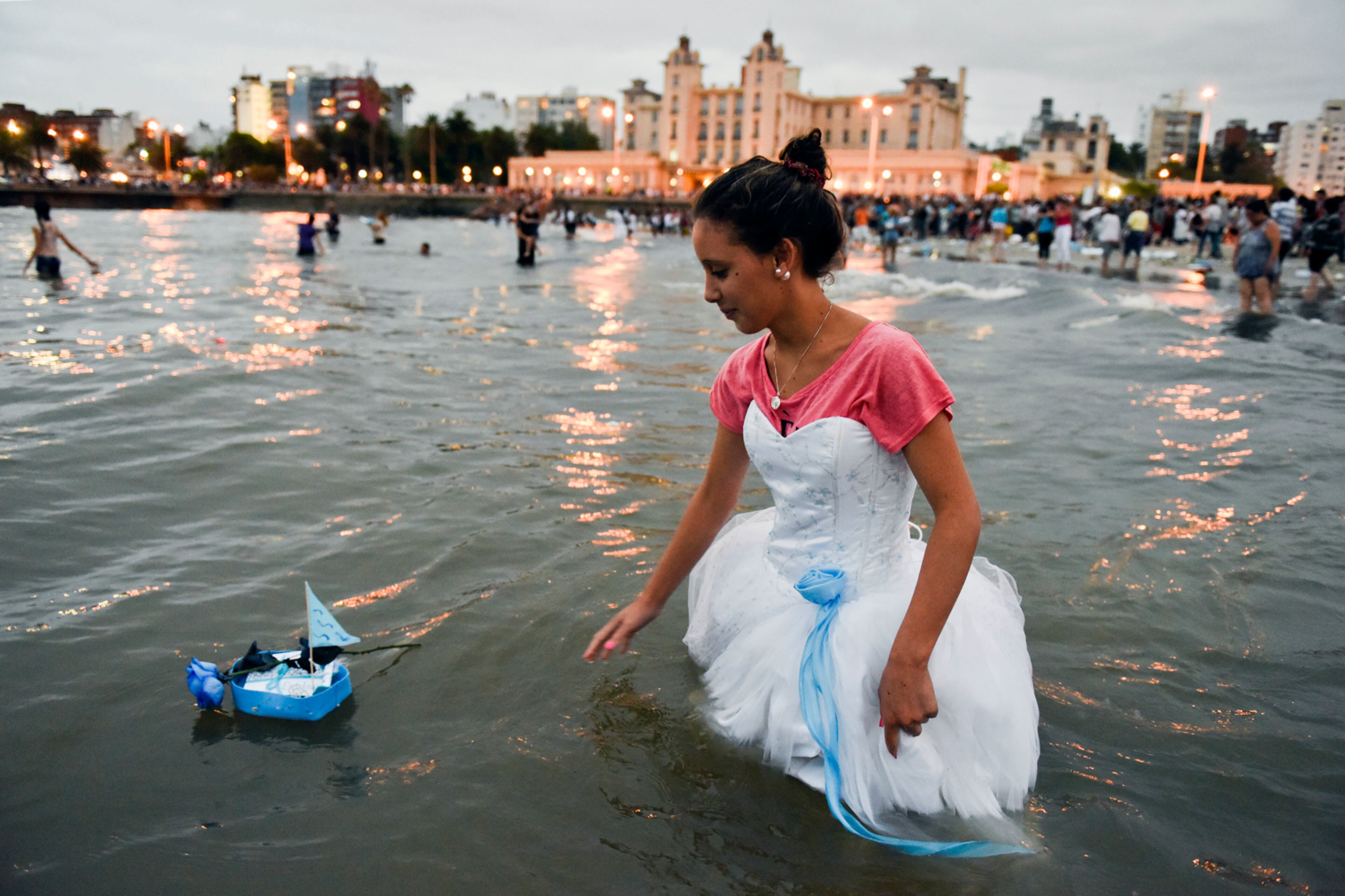 A woman releases a small boat as an offering for the African sea goddess Yemanja, at a beach in Montevideo, Uruguay, Thursday, Feb. 2, 2017. Thousands of worshippers come to the beach on Yemanja's feast day, bearing candles, flowers, perfumes and fruit to show their gratitude for her blessings. The celebration coincides with the Roman Catholic feast day of the Virgin of Candelaria, marked Feb. 2. (AP Photo/Matilde Campodonico)