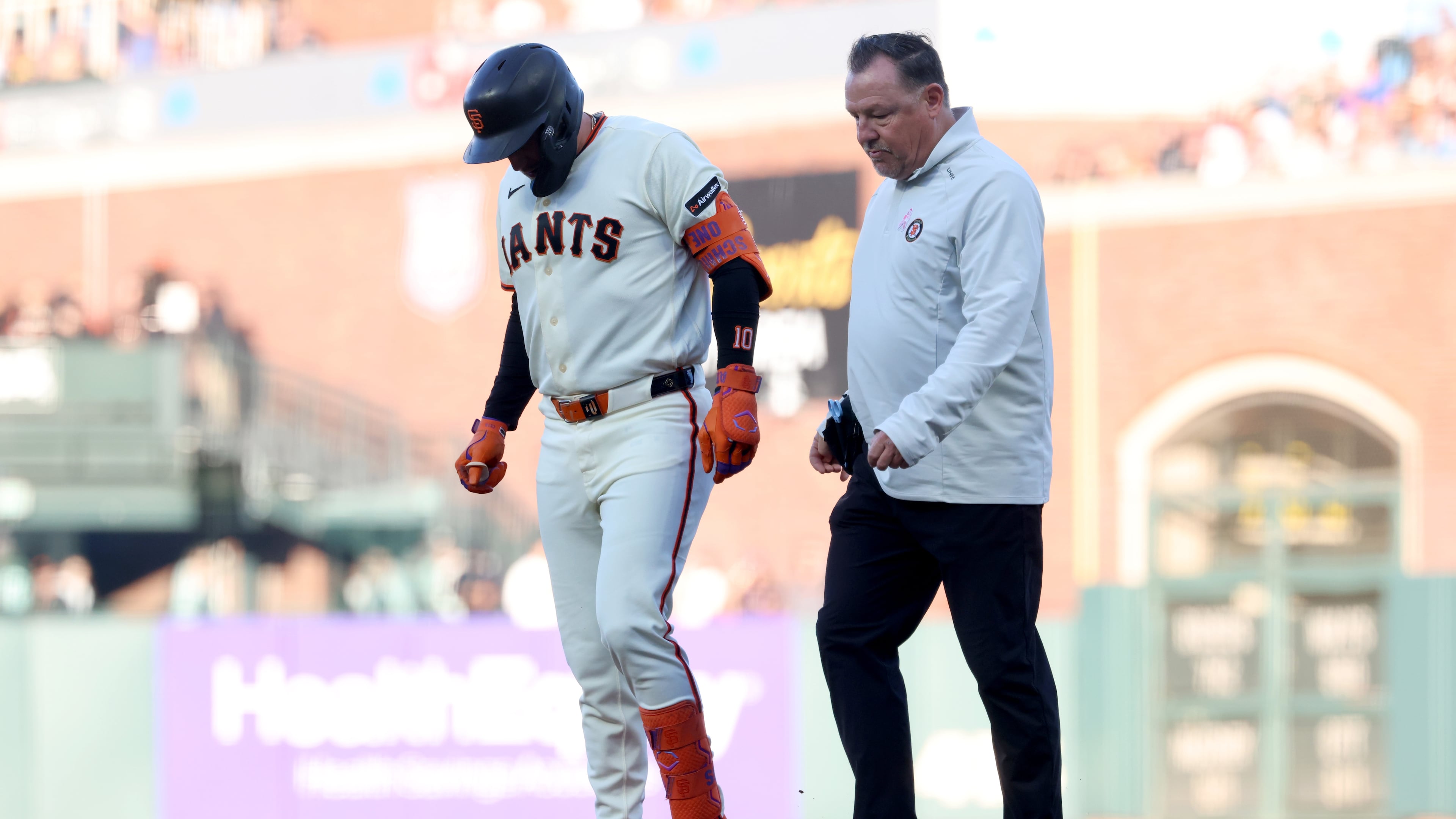 San Francisco Giants' Casey Schmitt, left, walks off the field with an injury accompanied by athletic trainer Dave Groeschner, right, during the second inning of a baseball game against the Milwaukee Brewers in San Francisco, Monday, July 27, 2026. (AP Photo/Jed Jacobsohn)