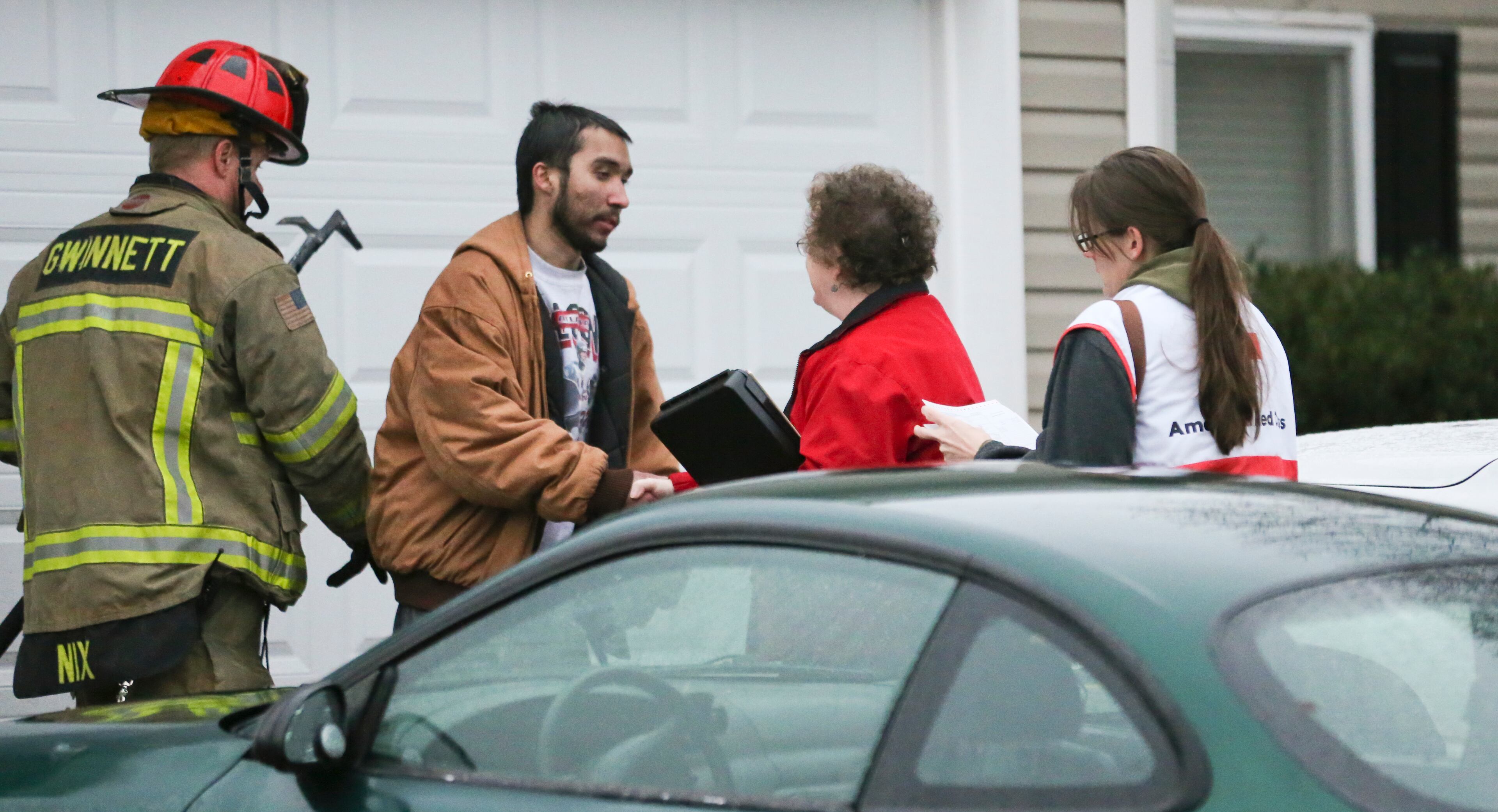 Red Cross workers and firefighters work with residents after thirteen people were displaced in a predawn fire that damaged four homes in a neighborhood near Lawrenceville.