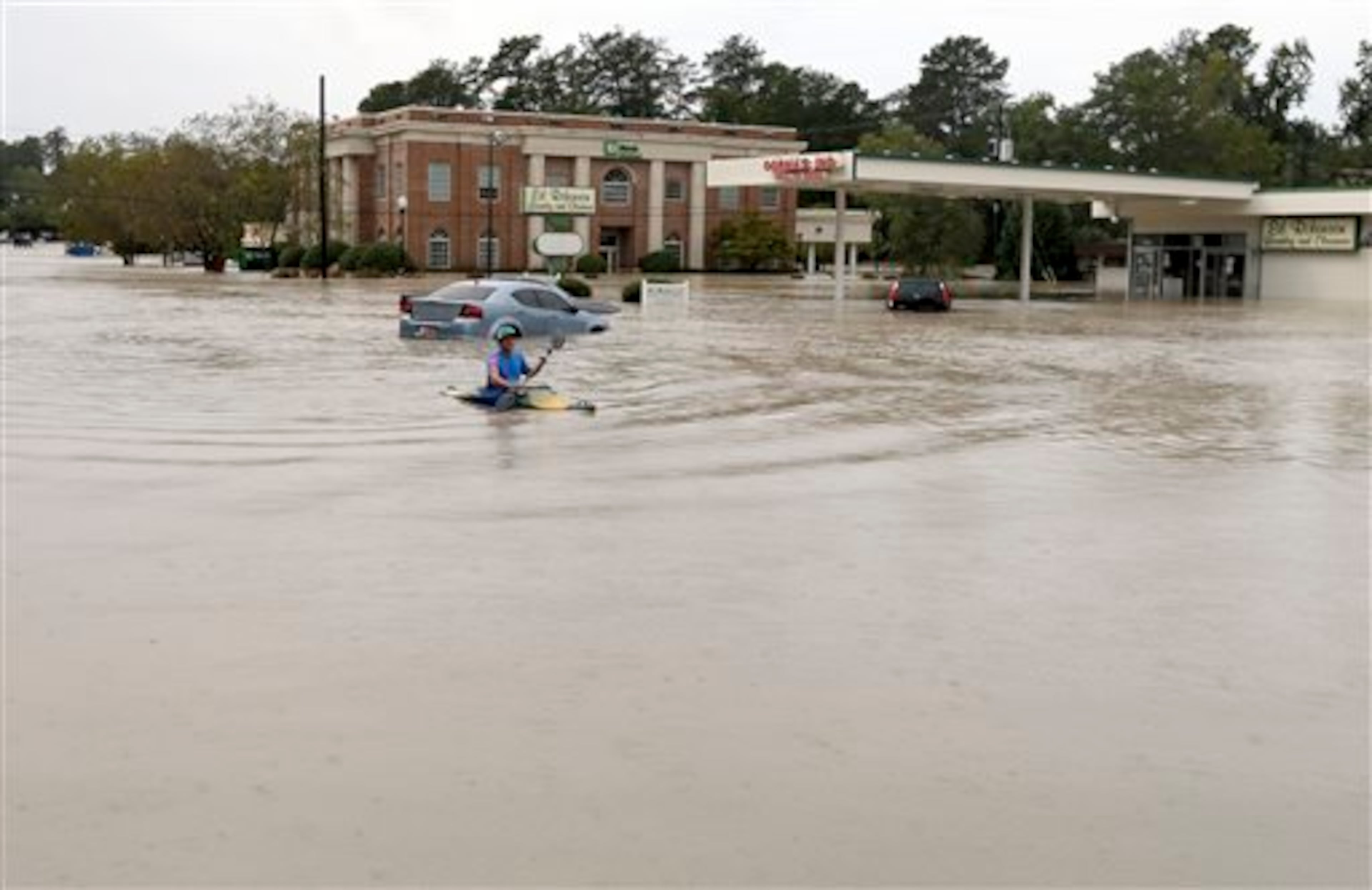 Jordan Bennett, of Rock Hill, S.C., paddles down a flooded a street in Columbia, S.C., Sunday, Oct. 4, 2015. The rainstorm drenching the U.S. East Coast brought more misery Sunday to South Carolina, cutting power to thousands, forcing hundreds of water rescues and closing many roads because of floodwaters. (AP Photo/Chuck Burton)