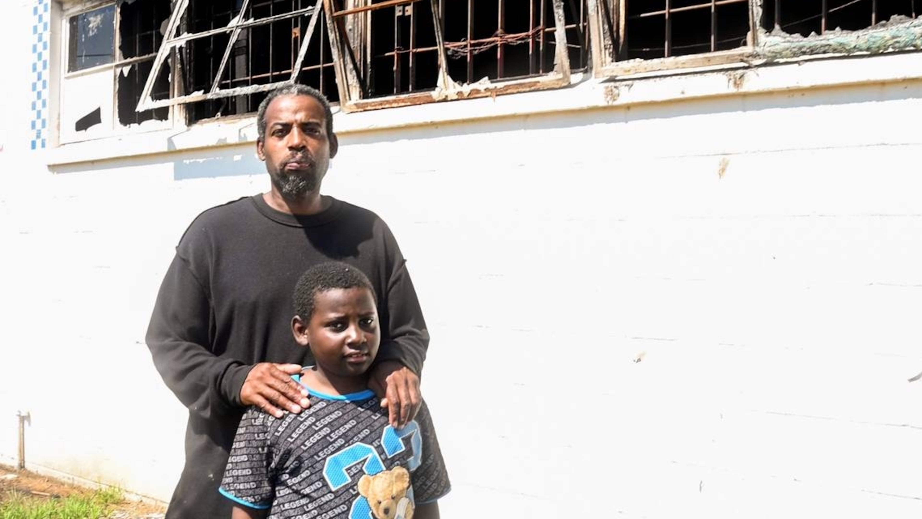 Tony Walker, and his son, 8-year-old son, Antonio, outside of what’s left of Doggie Dogs, his walk-up hot dog restaurant that was destroyed by a fire. (Photo Courtesy of Jason Vorhees/The Telegraph)