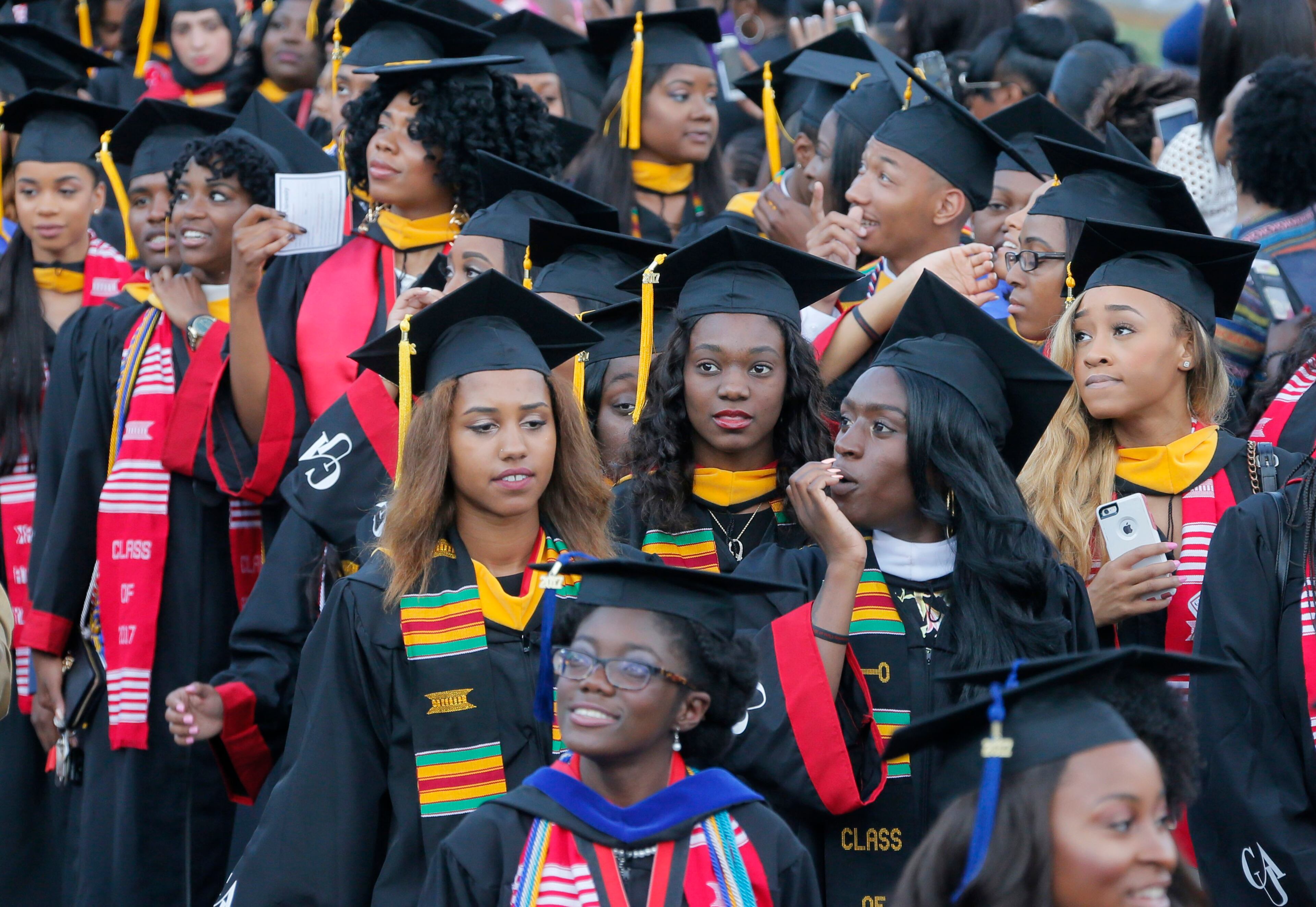 5/22/17 - Atlanta - Some graduates look toward the stands and family members, while others are on their phones as they enter during the Processional. Clark Atlanta University's Panther Stadium was the site of their 28th annual Commencement. Businessman William Pickard gave the commencement address. Rev. Jesse Jackson, who received an honorary degree, also spoke. Panther Stadium, BOB ANDRES /BANDRES@AJC.COM