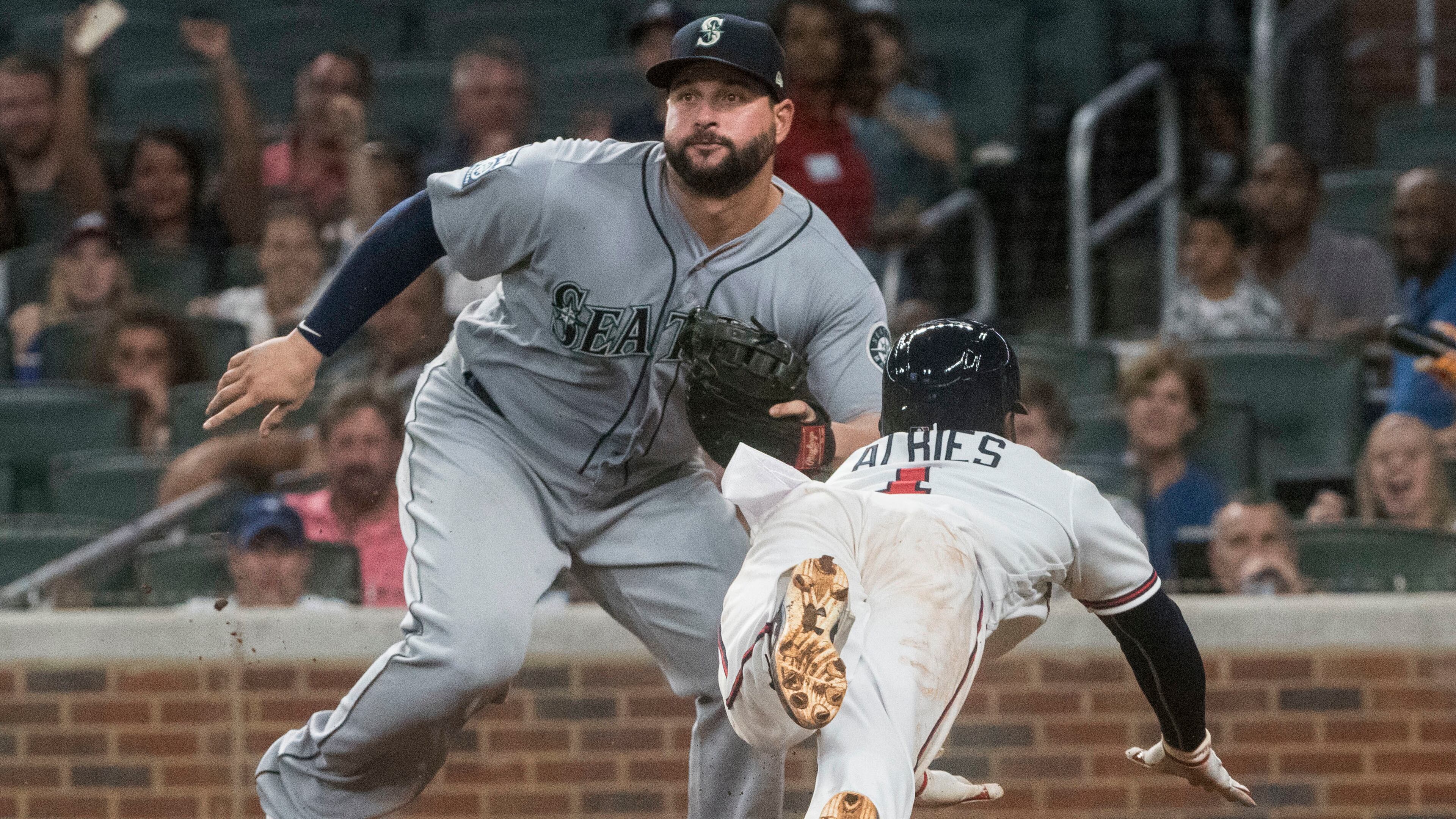 Atlanta Braves second baseman Ozzie Albies dives to home plate to score as Seattle Mariners first baseman Yonder Alonso waits for the throw after a rundown on the third base line during the sixth inning of a baseball game, Tuesday, Aug. 22, 2017, in Atlanta. (AP Photo/John Amis)