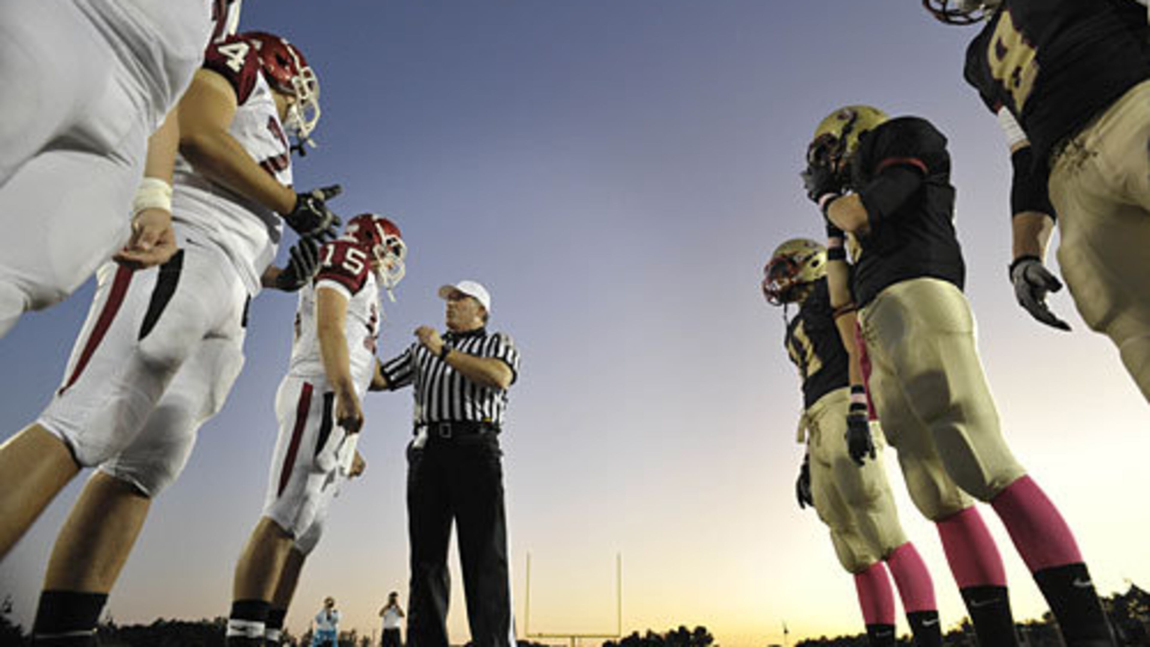 An official talks with with Lambert's David Broadus (15) as captains meet before the start of the football game against Johns Creek, Friday, Oct. 7, 2011.