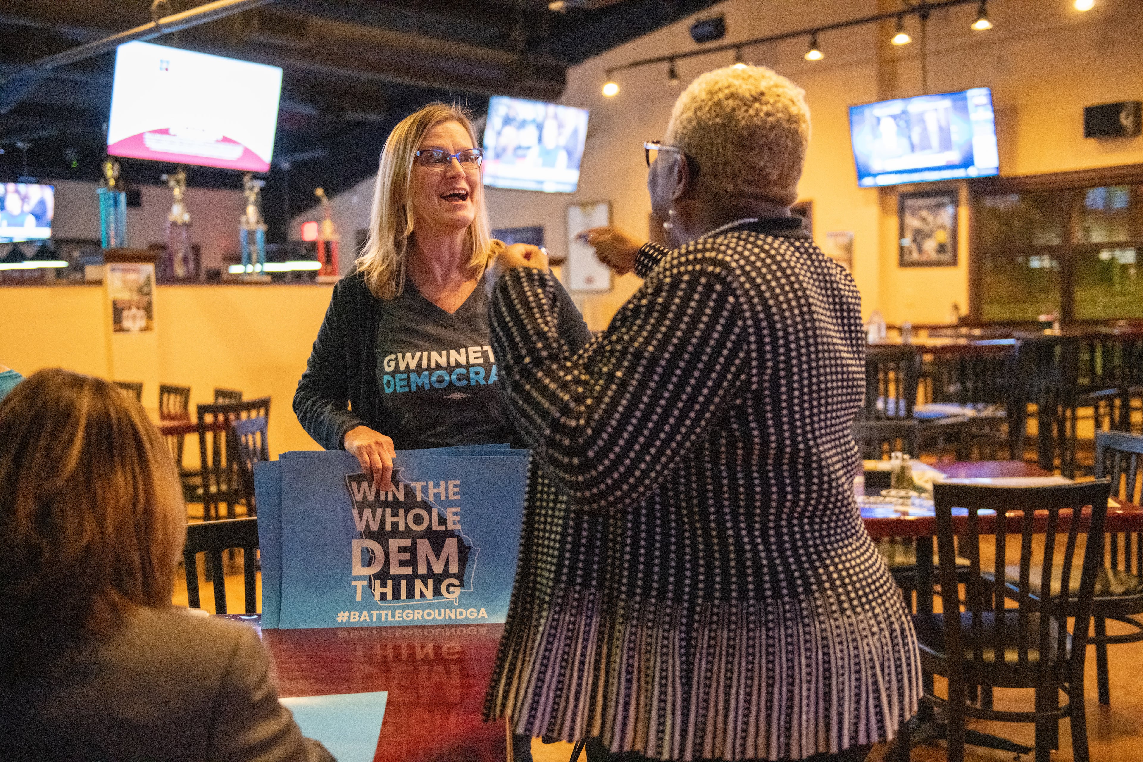 From left, Penny Bernath, Chair of Campaign Elections, greets Pinkie Farver, the District Director for the Georgia Federation of Democratic Women before they watch the presidential debates held in Atlanta Wednesday, November 20, 2019 at Mazzy's Sports Bar in Norcross, Ga.
PHOTO BY ELISSA BENZIE