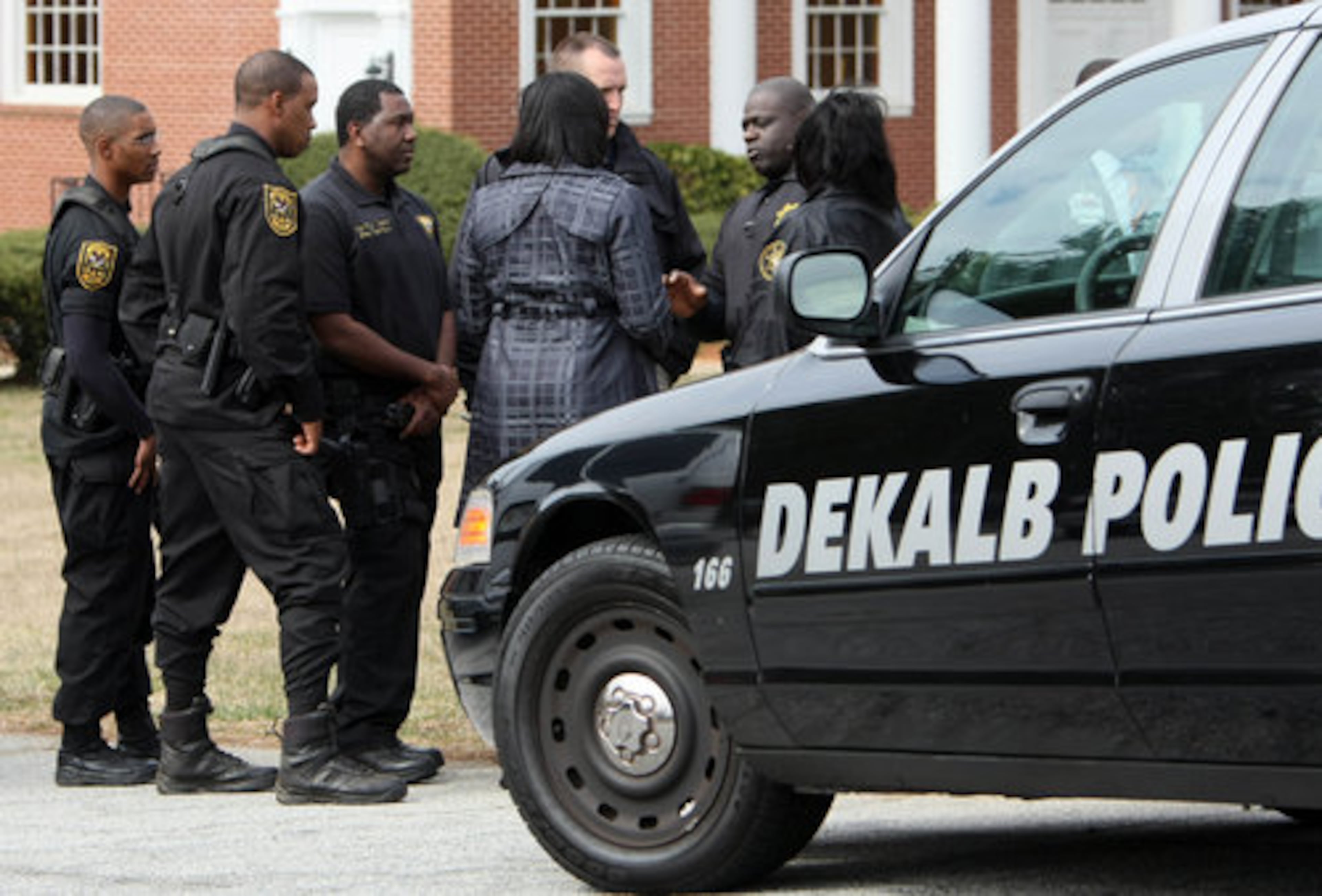 DeKalb County Public Information Officer Mekka Parrish (center with back to camera) gets briefed by DeKalb County police before speaking to the media.