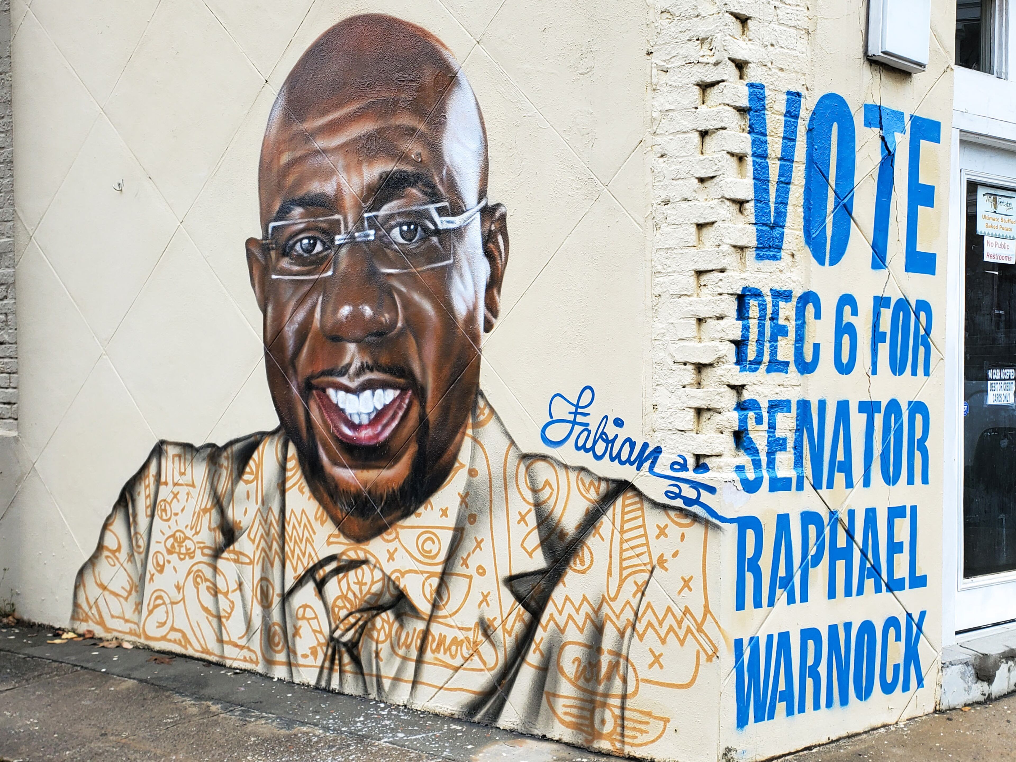 At the intersection with Inman Street, you'll see Fabian Williams' portrait of Rev. Raphael Warnock’s smiling countenance reminding residents to vote.