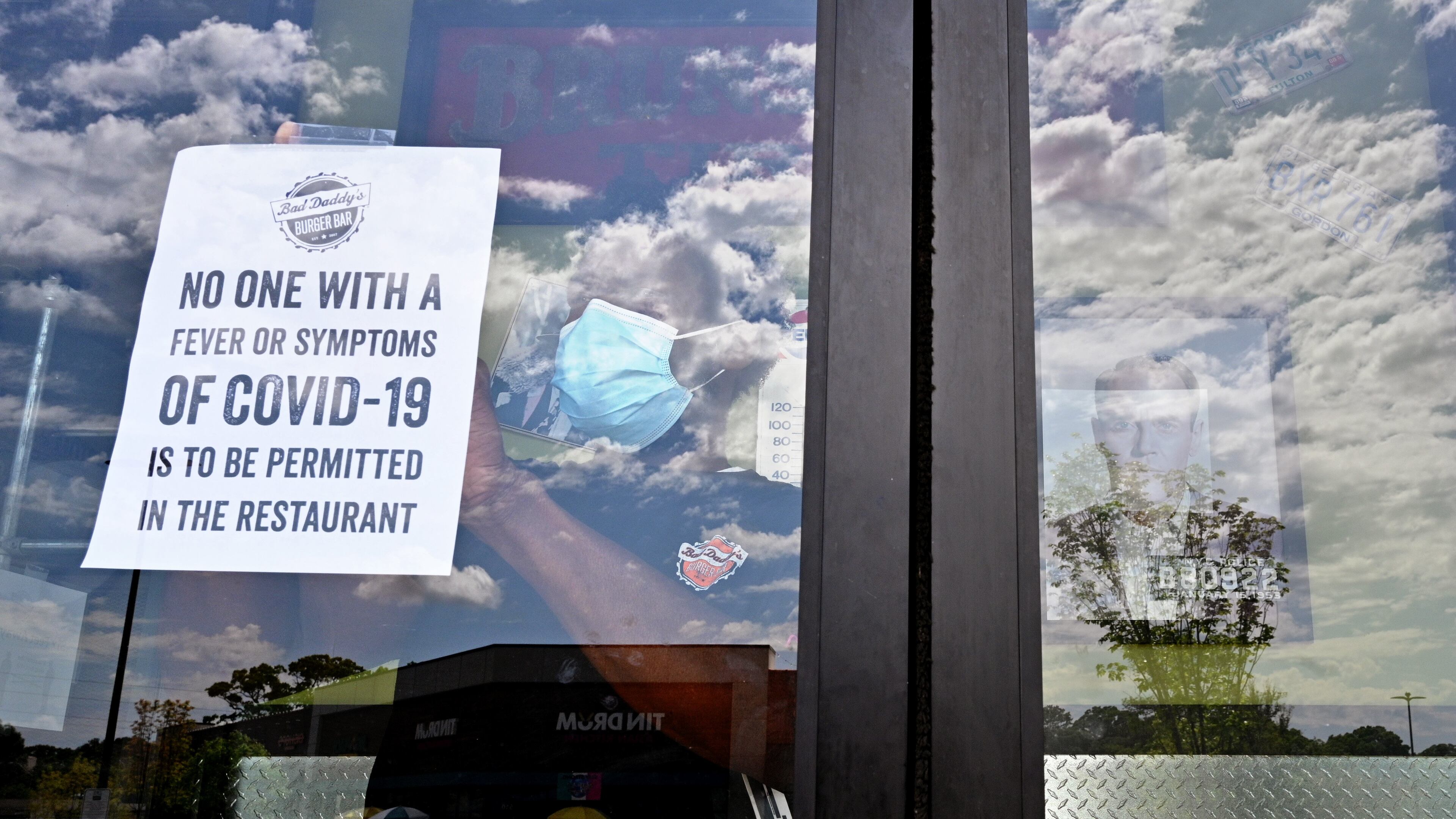 An employee posts a warning sign at the main door of Bad Daddy's Burger Bar in the Decatur area on Saturday, April 25. (Hyosub Shin / Hyosub.Shin@ajc.com)