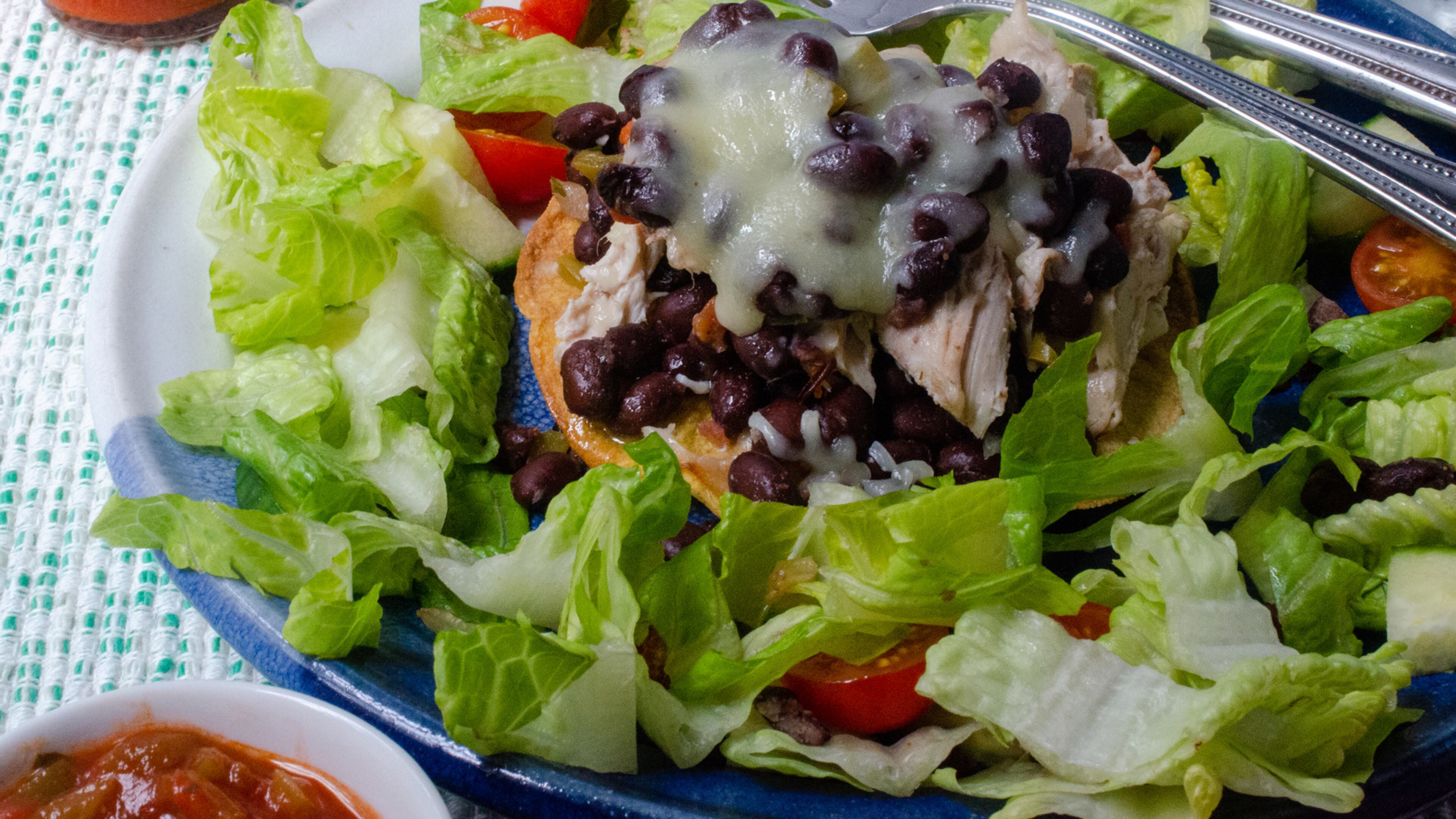 A black bean and chicken tostada topped with melted cheese and served with a lettuce salad makes for a healthy Tex-Mex meal.
(Virginia Willis for The Atlanta Journal-Constitution)