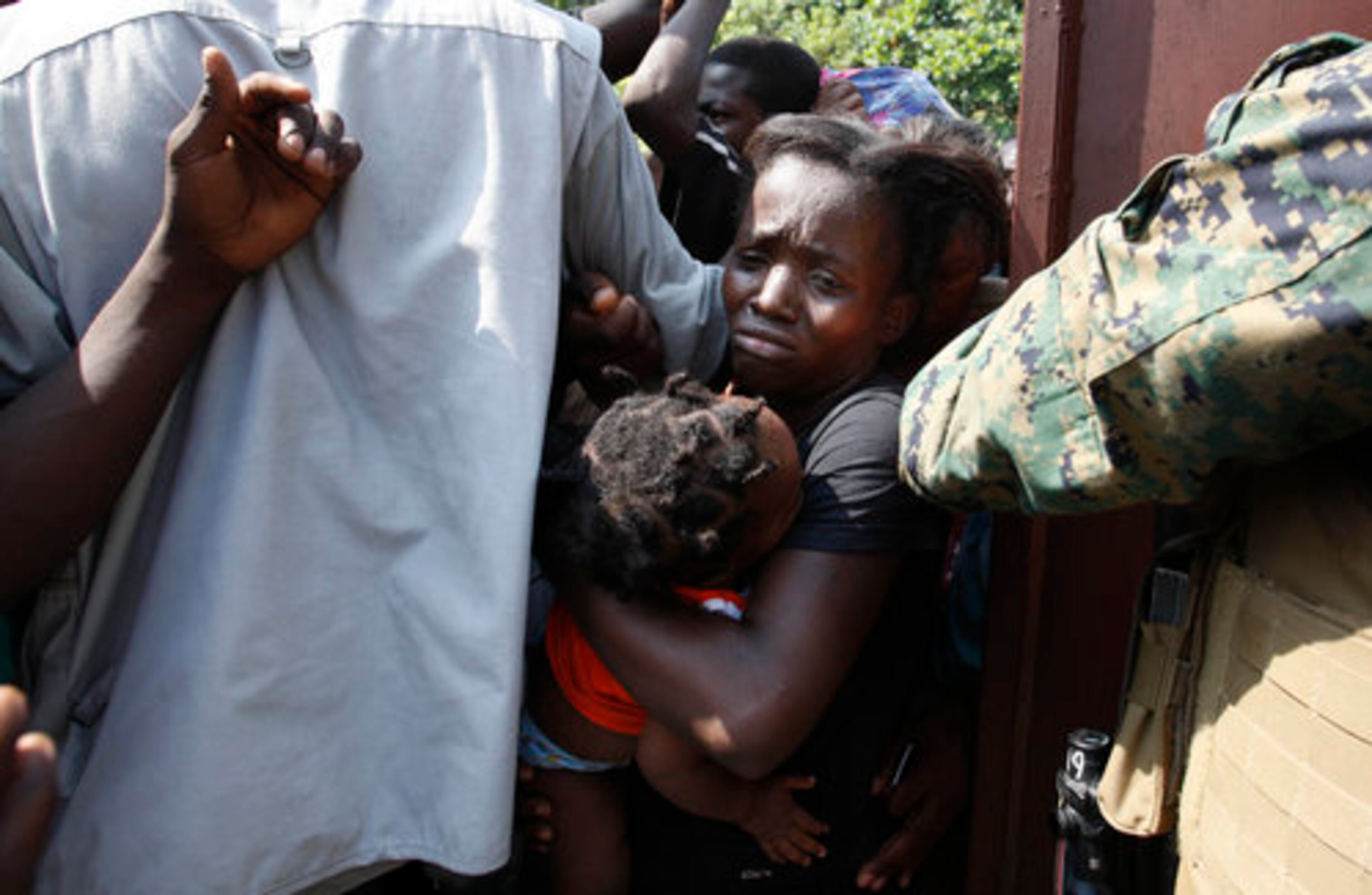 A woman carries her child through a surging crowd as U.S. Marines tried to control access to a food distribution point in Leogane, Wednesday, Jan. 21, 2010. On Tuesday about 125 marines landed in Leogane, a fishing town on the north shore of Haiti's southern peninsula, to distribute food and water.