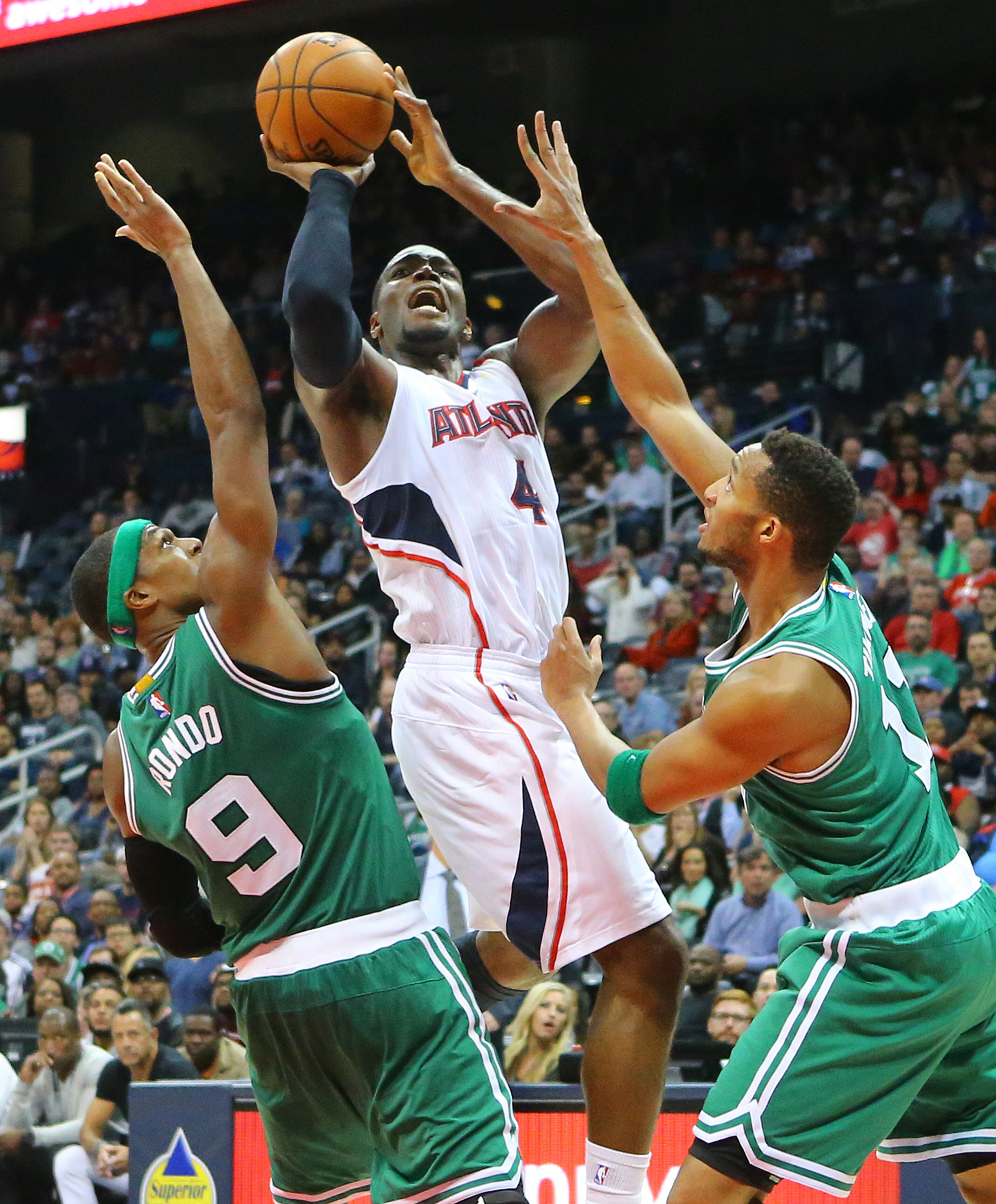 Hawks forward Paul Millsap draws the foul from Celtics defenders Rajon Rondo (left) and Evan Turner on the way to beating the Celtics 109-105 in an NBA basketball game on Tuesday, Dec. 2, 2014, in Atlanta. CURTIS COMPTON / CCOMPTON@AJC.COM