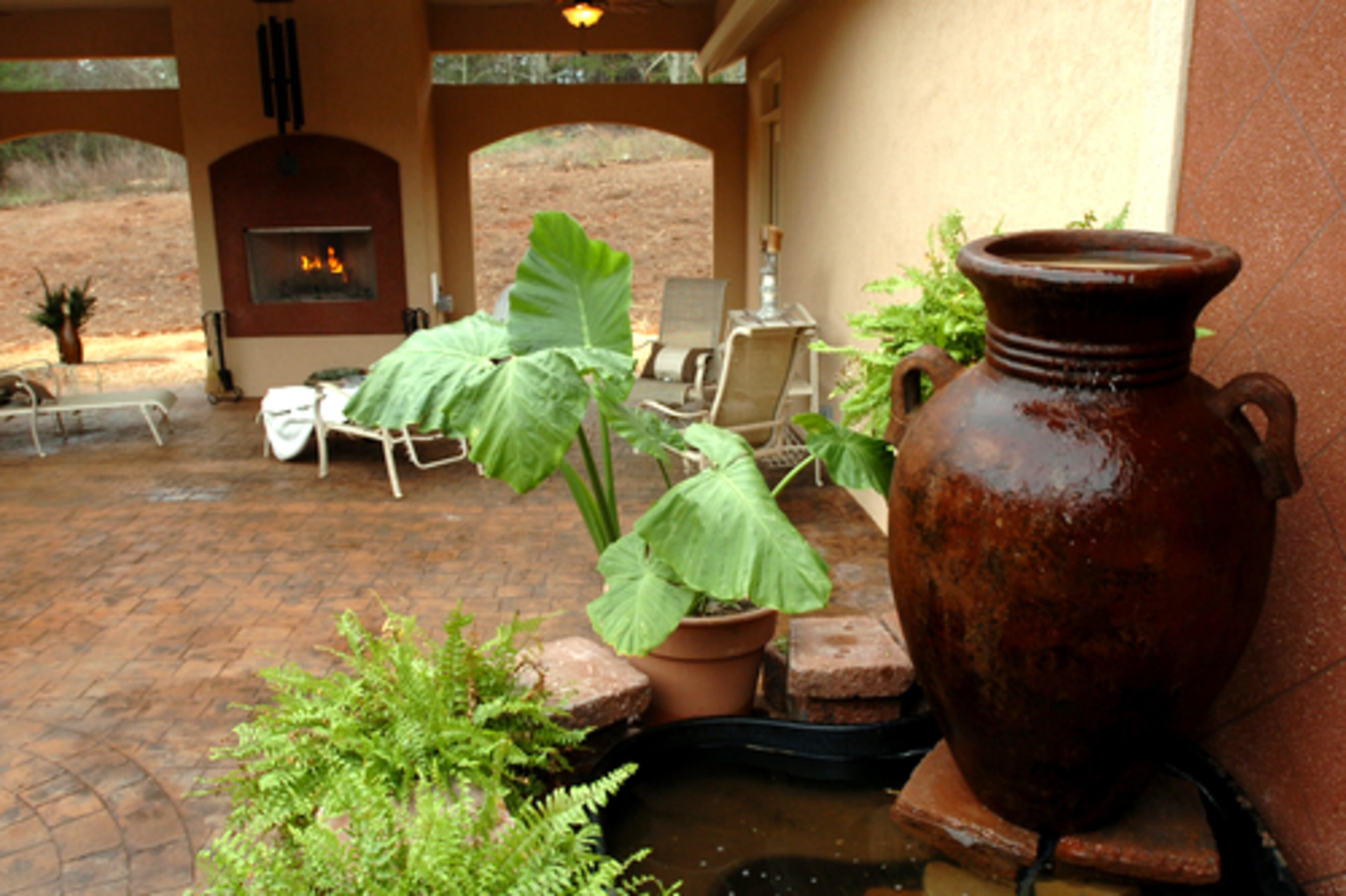 Around the one-story tan stucco exterior is a wide wraparound veranda, floored with stamped concrete pavers.