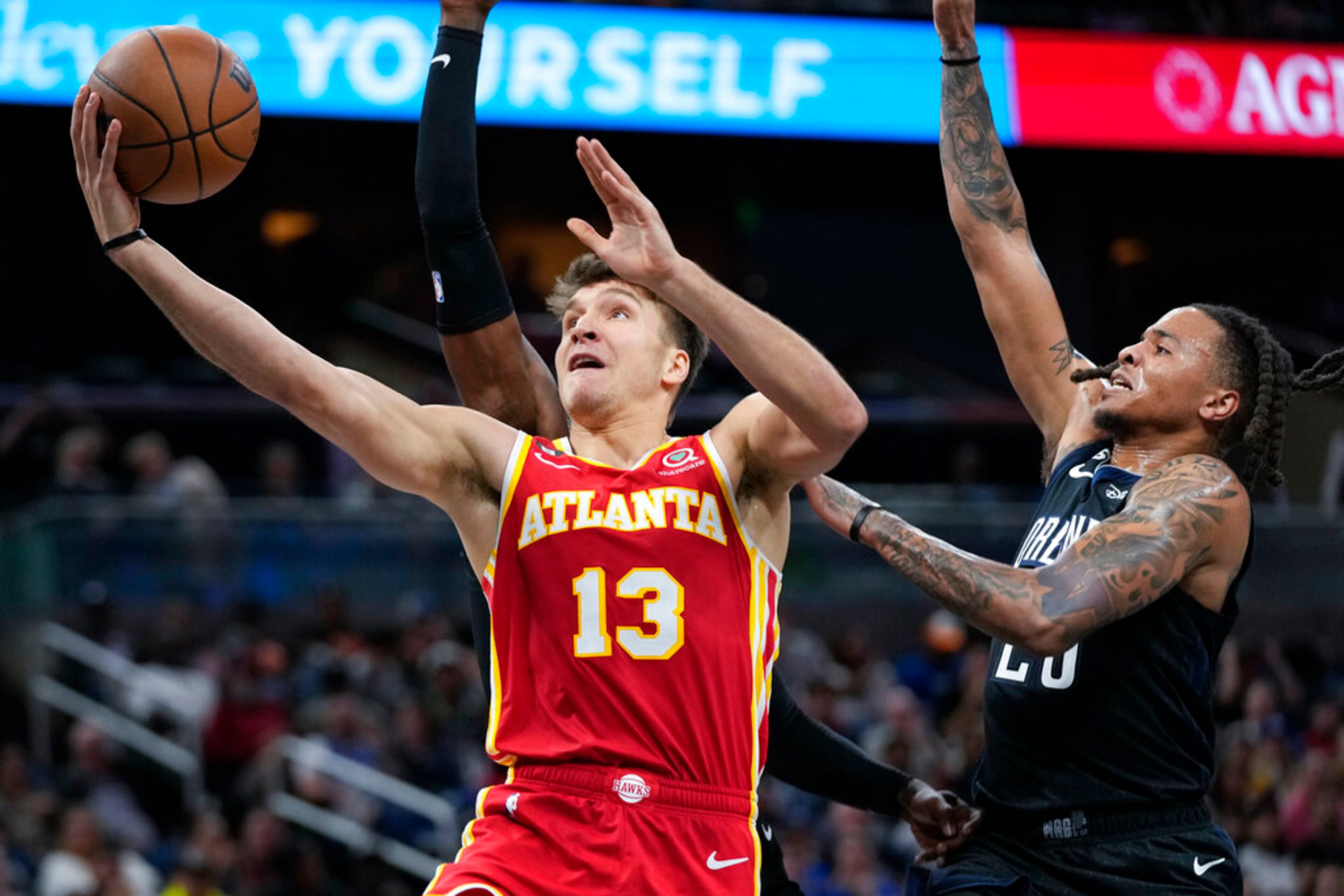 Atlanta Hawks' Bogdan Bogdanovic (13) goes past Orlando Magic's Markelle Fultz for a shot during the first half of an NBA basketball game, Wednesday, Dec. 14, 2022, in Orlando, Fla. (AP Photo/John Raoux)
