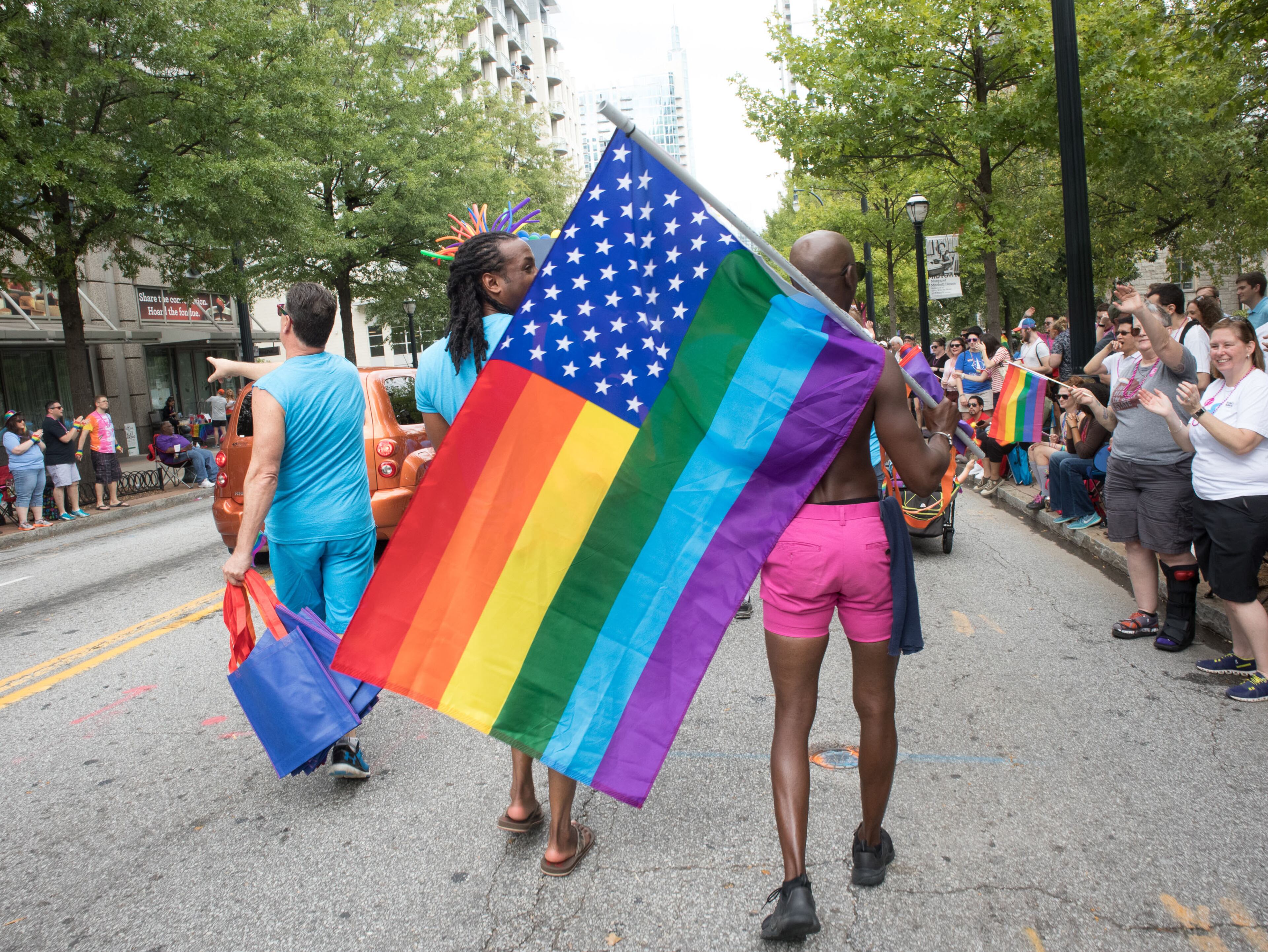 People head down Peachtree Street with flags during the Atlanta Pride Parade Sunday, October 15, 2017. STEVE SCHAEFER / SPECIAL TO THE AJC