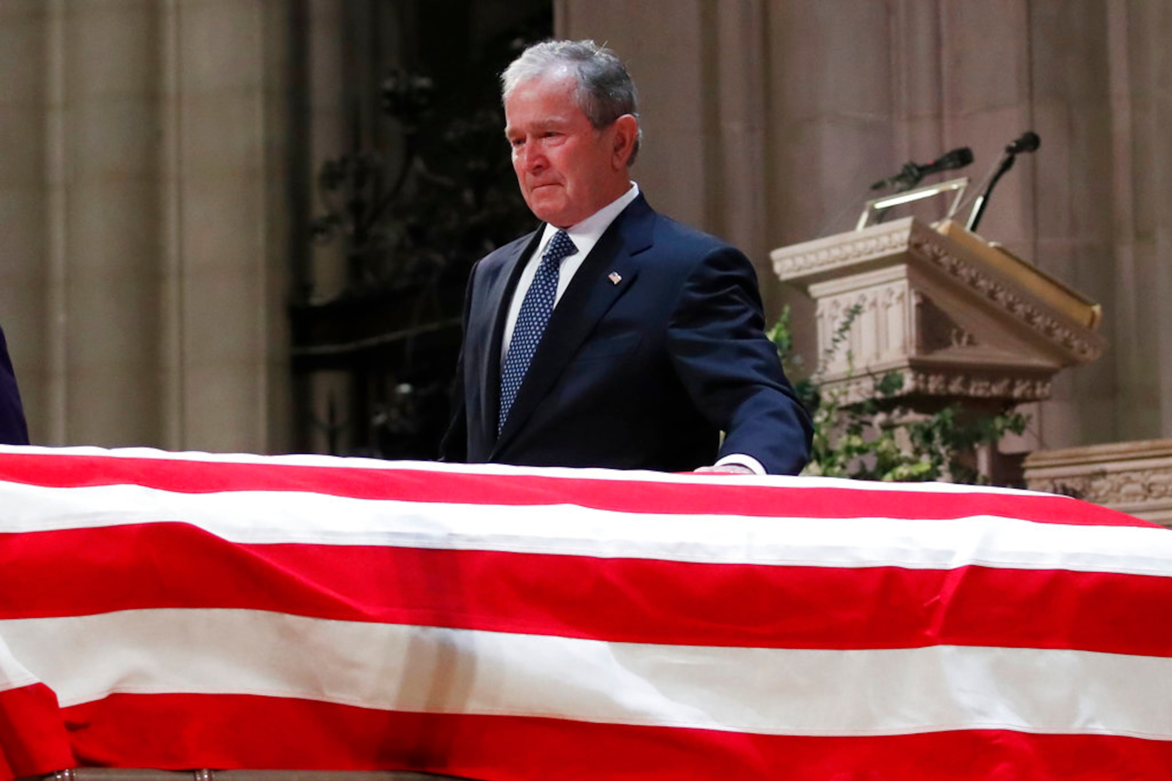 Former President George W. Bush touches the casket of his father, former President George H.W. Bush, at the State Funeral at the National Cathedral, Wednesday, Dec. 5, 2018, in Washington. (AP Photo/Alex Brandon, Pool)