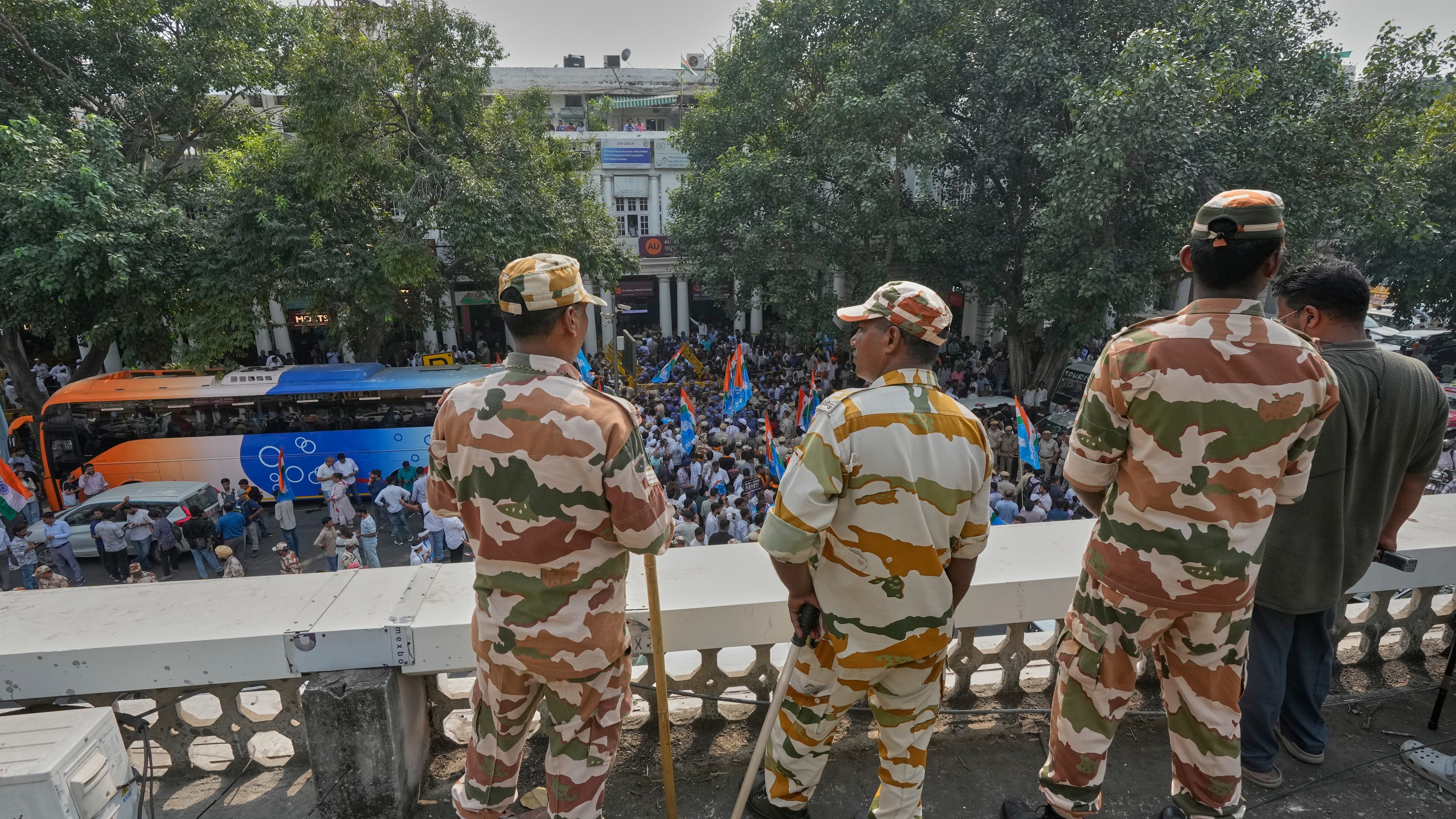 Security personnel keep vigil from the rooftop of a building as members of the student wing of India's Congress party and other protesters gather to start a march demanding the resignation of the country's election chief Gyanesh Kumar, in New Delhi, India, Thursday, Oct. 8, 2026. (AP Photo/Manish Swarup)