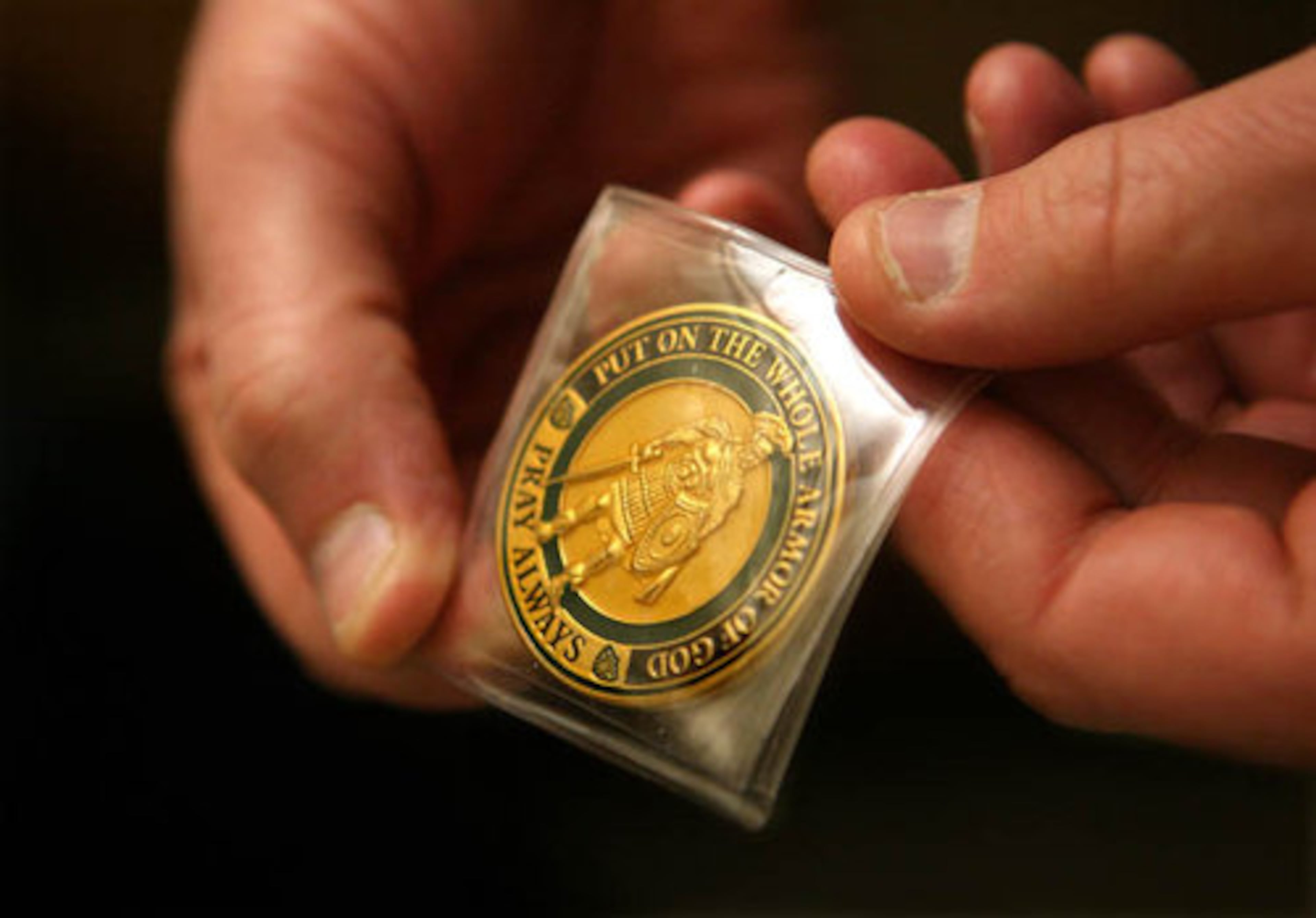 Turner takes out the coin he's carried with him from Baghdad to give to Battle. Decorated with a sword representing honor and a breastplate of righteousness, the shiny medal is Turner's way of bestowing hope to the wounded. A verse from Ephesians is etched on one side: "Put on the whole armor of God. Pray always."