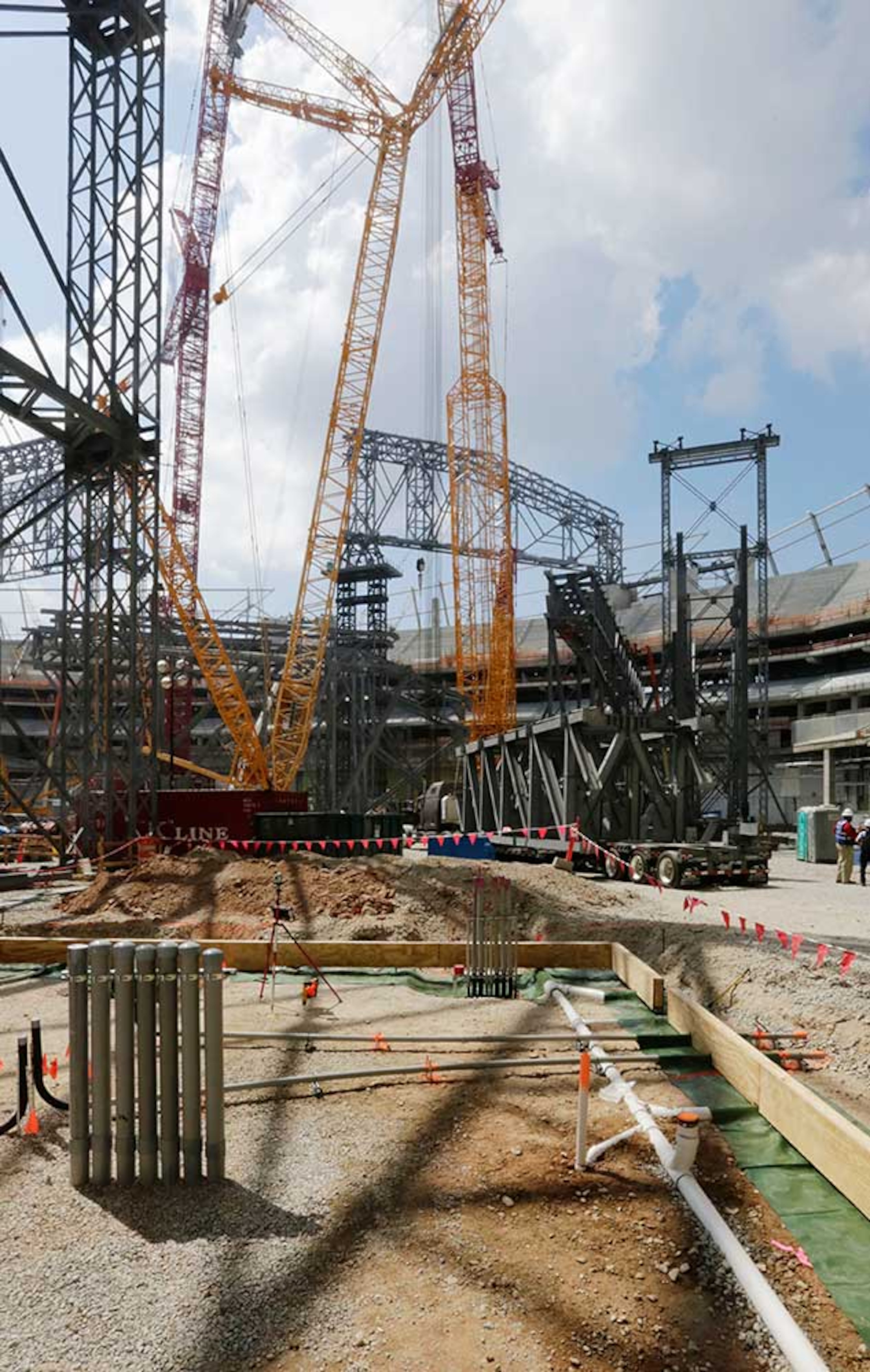 The field level is filled with steel work and cranes as tower construction and roof steel truss ground assembly continues inside the bowl.